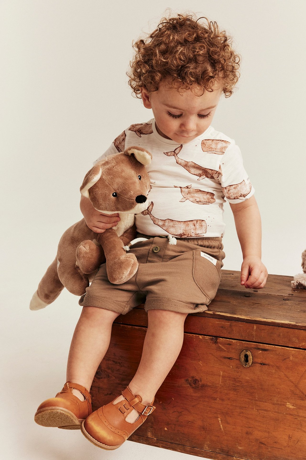 Braune Slub-Jersey-Shorts mit Kordelzug an einem Kind, gestylt mit einem Wal-T-Shirt und braunen Schuhen.