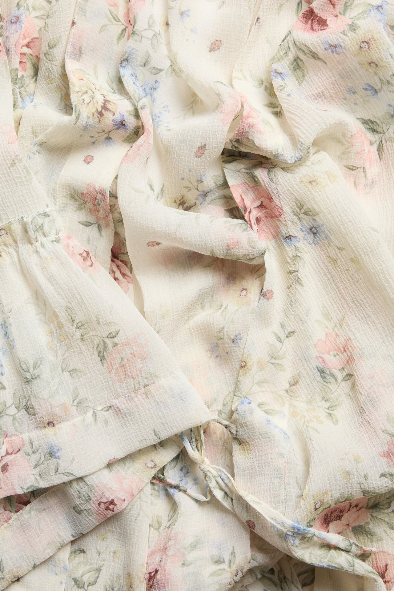 Nahaufnahme eines cremefarbenen floralen Chiffon-Kimonos mit rosa, blauen, grünen Blumen und gebundenem Gürtel.