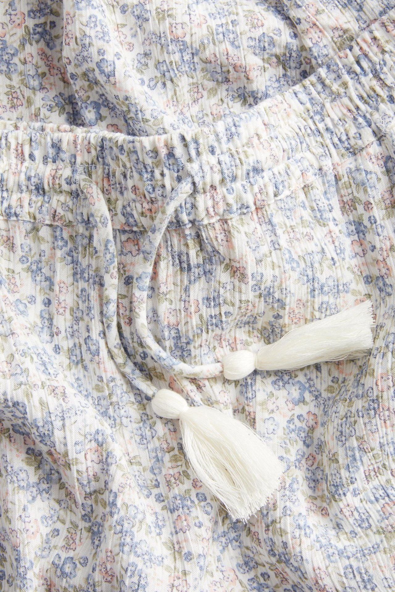 Close-up: offwhite floral crepe viskos long skirt, elasticated drawstring waist with white tassels.