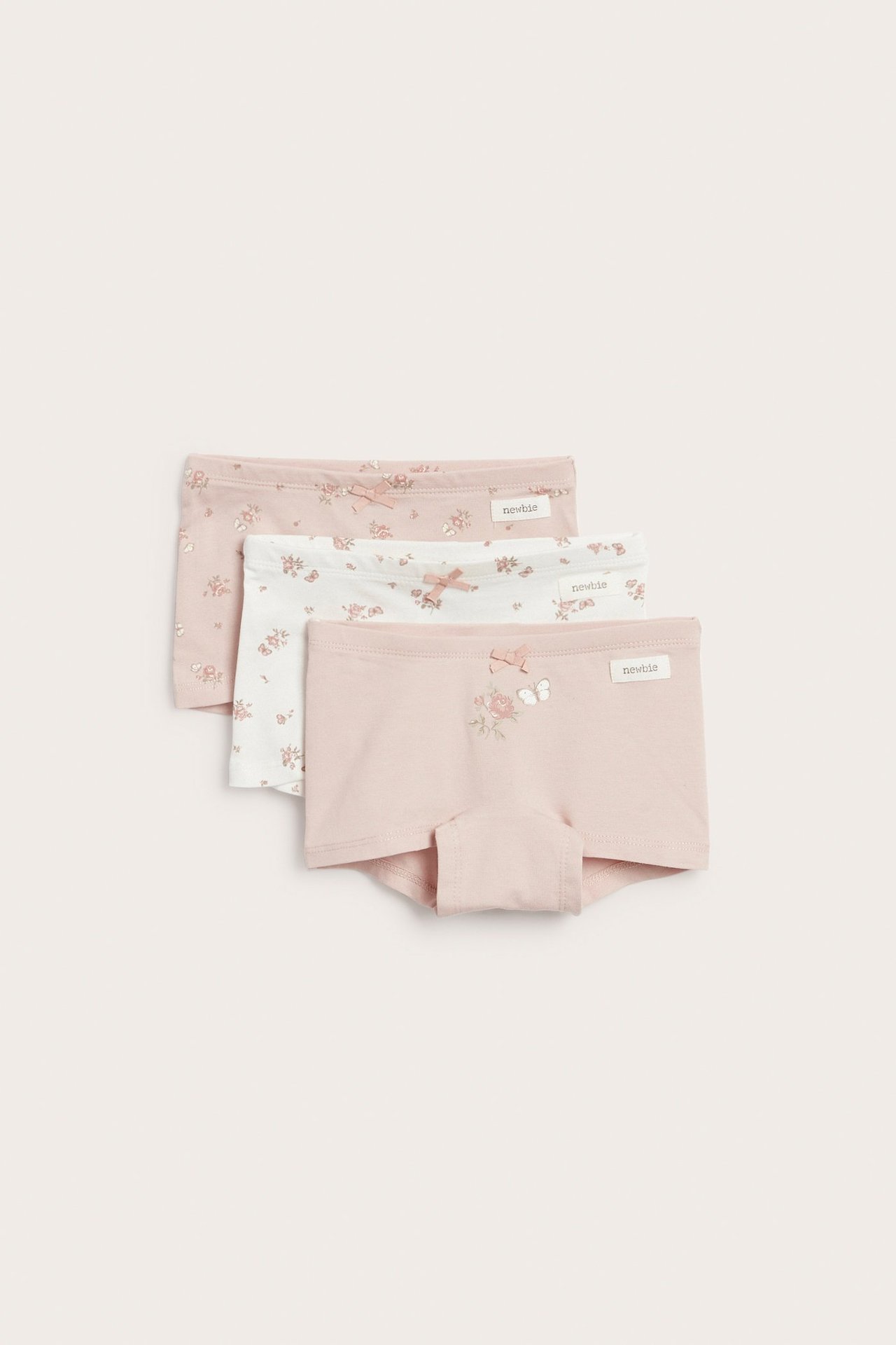 Front view of a kid's pink boxer brief with roses and butterflies, plus white and light pink floral pairs.