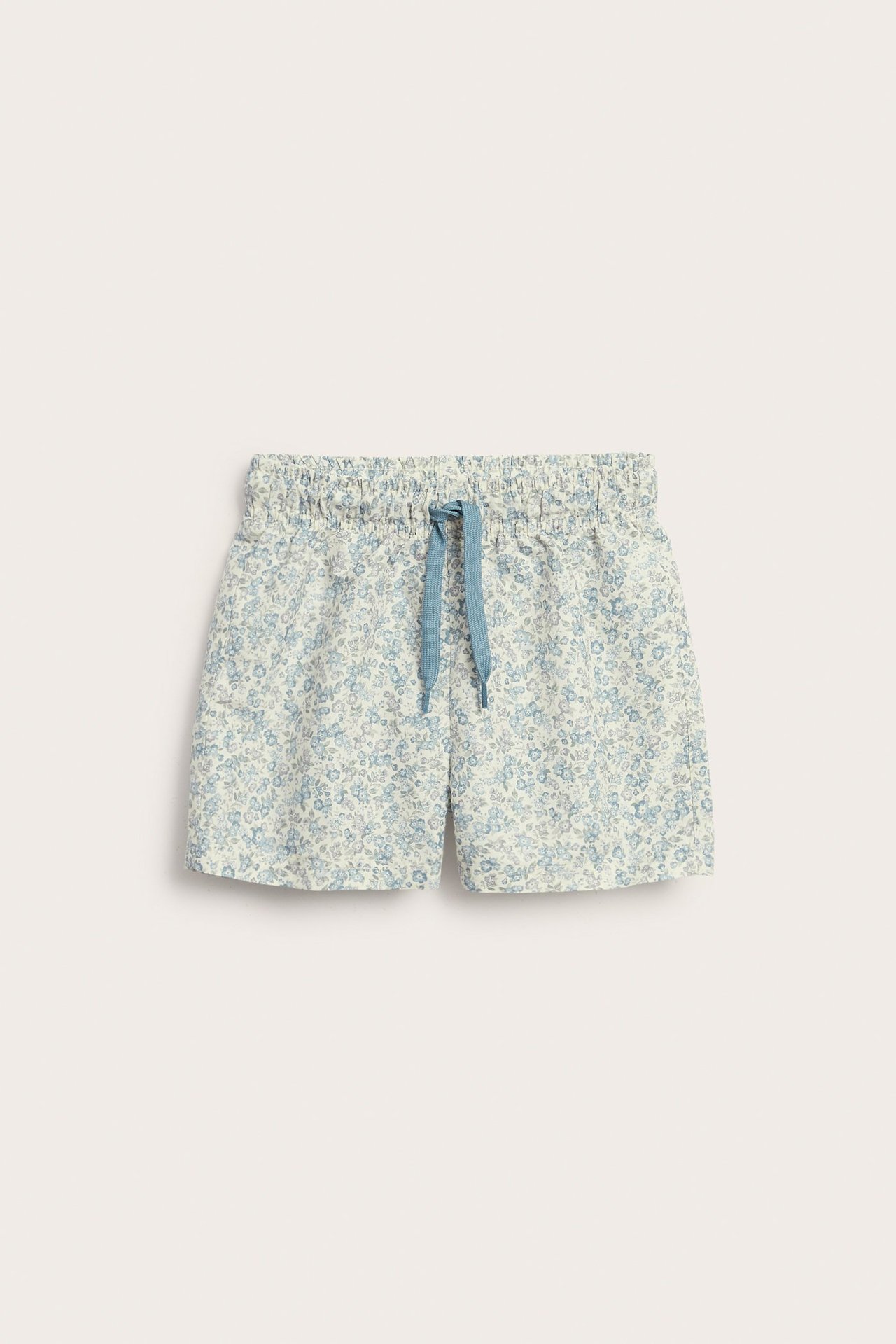 Front view of kid's light blue floral swim shorts with an elasticated waist and blue drawstring.