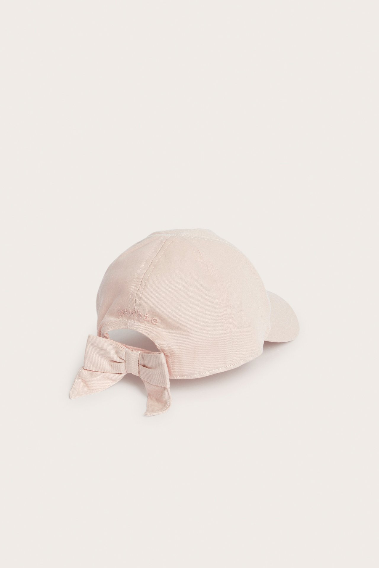 Back-right view of a light pink kid's cap with a decorative bow and 'Newbie' embroidery at the back.