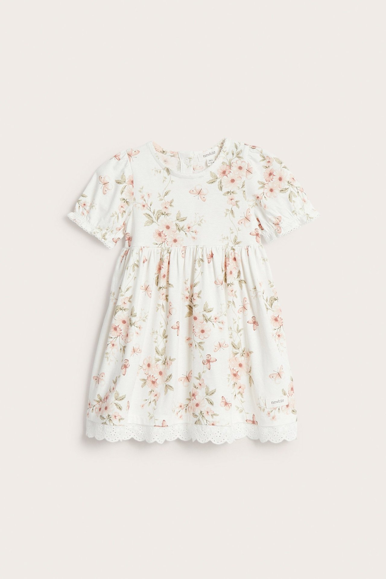 Vorderansicht eines cremeweißen Kinder-Jerseykleides mit Blumen- und Schmetterlingsmuster, Puffärmeln und Spitzenborte.