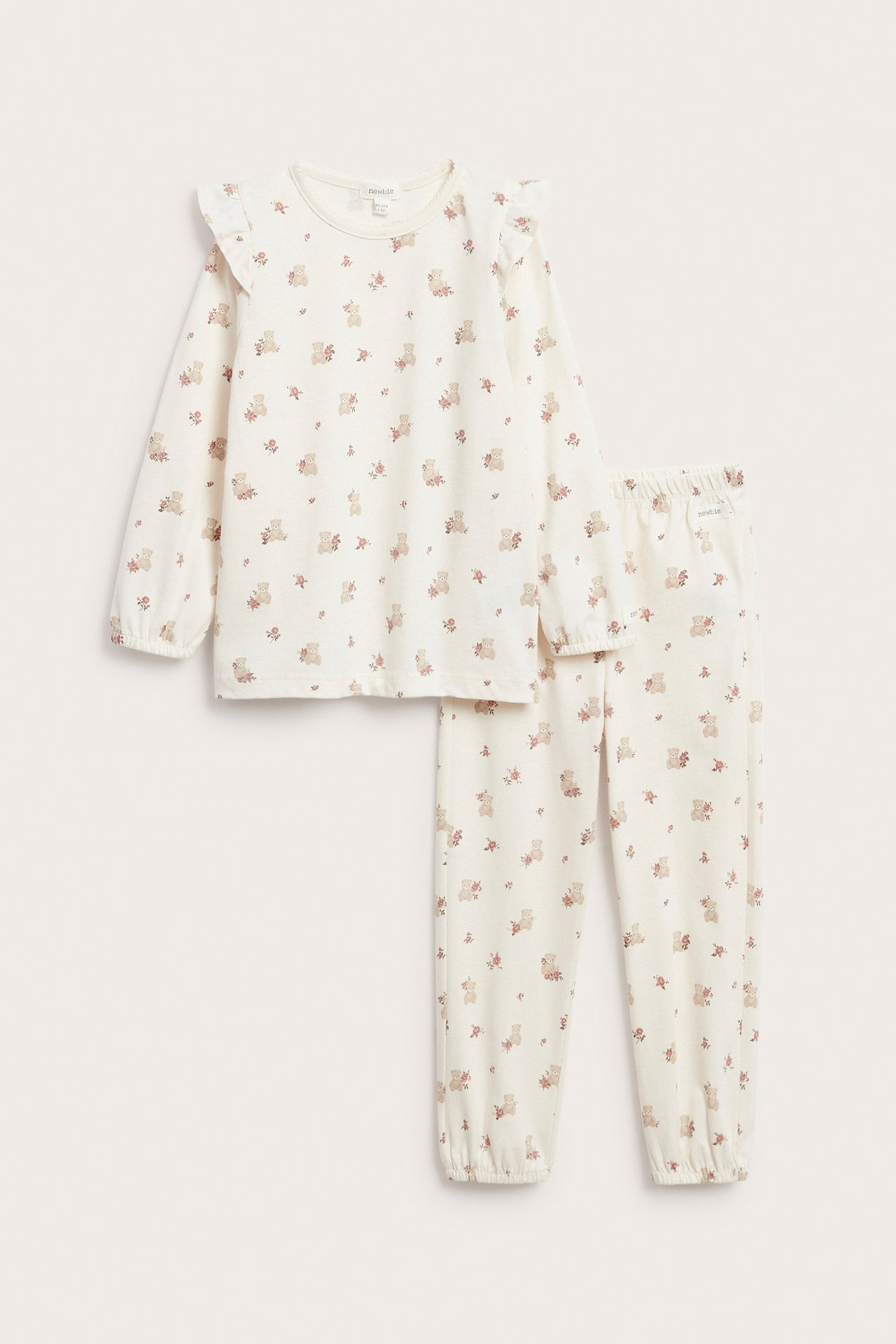 Front view: Off-white cotton kids' pyjamas with teddy bear and rose print, featuring ruffled shoulders.