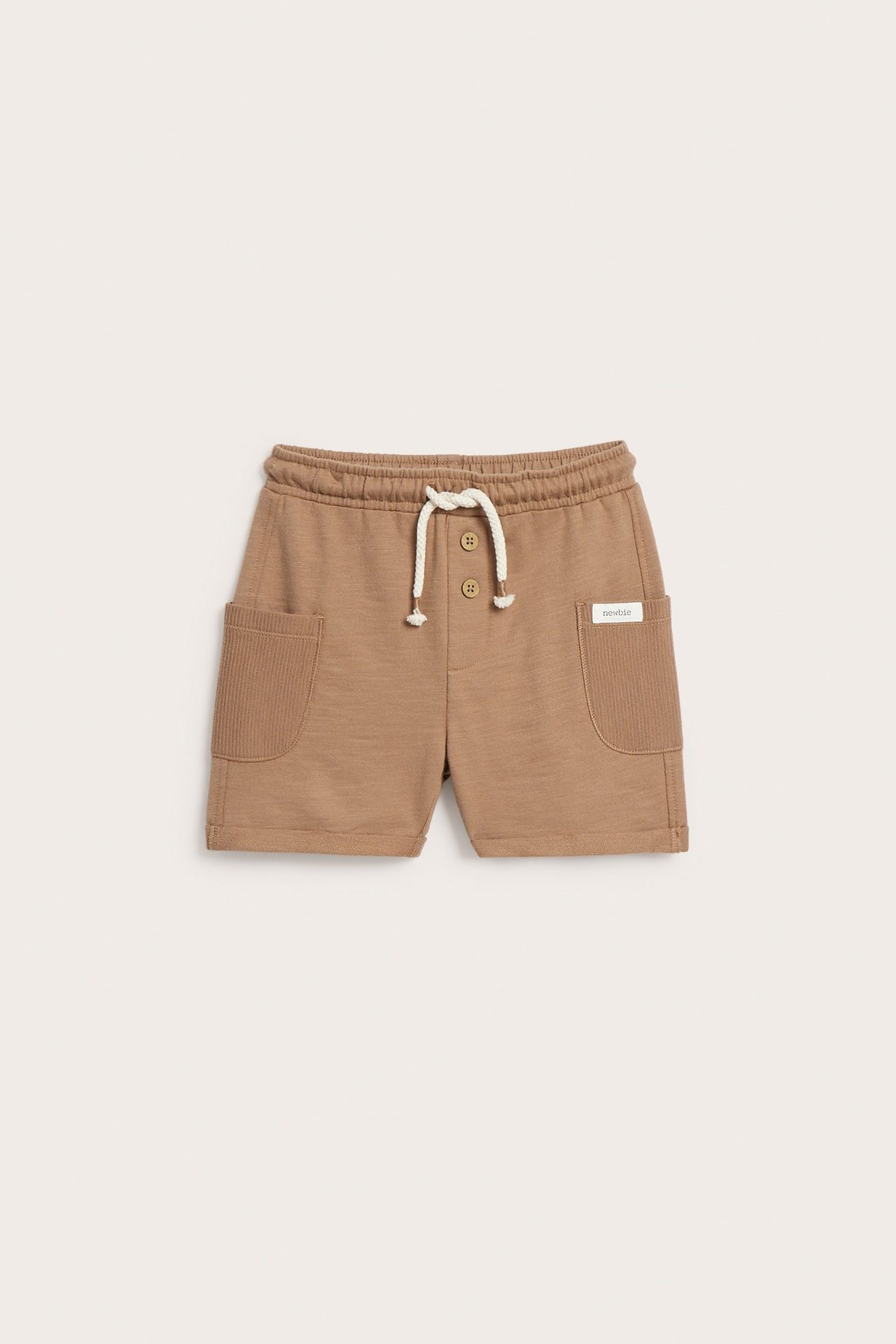 Vorderansicht: braune Kinder-Slub-Jersey-Shorts aus Baumwolle mit gerippten Seitentaschen, Knöpfen und weißem Kordelzug.