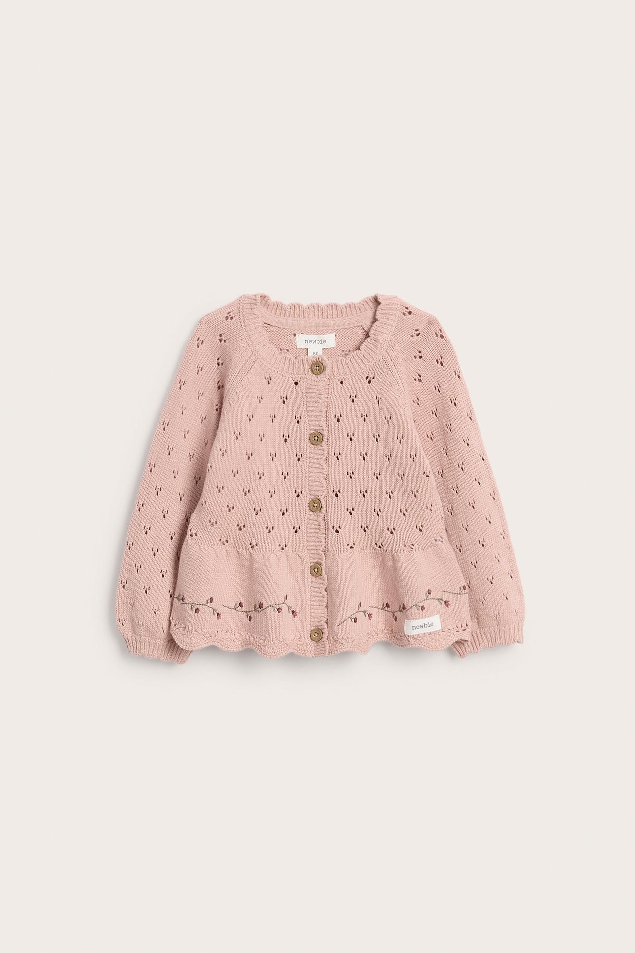 Vorderansicht einer rosafarbenen gestrickten Baby-Strickjacke mit Lochmuster, Blumenstickerei und Knöpfen.