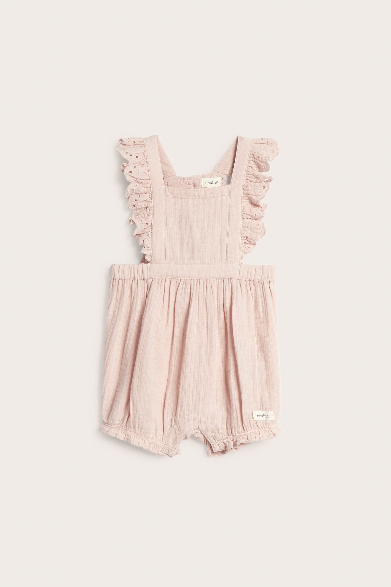 Vorderansicht von hellrosa gewebten Baby-Latzshorts mit Rüschenspitzen-Trägern und Gummizügen an den Beinen.