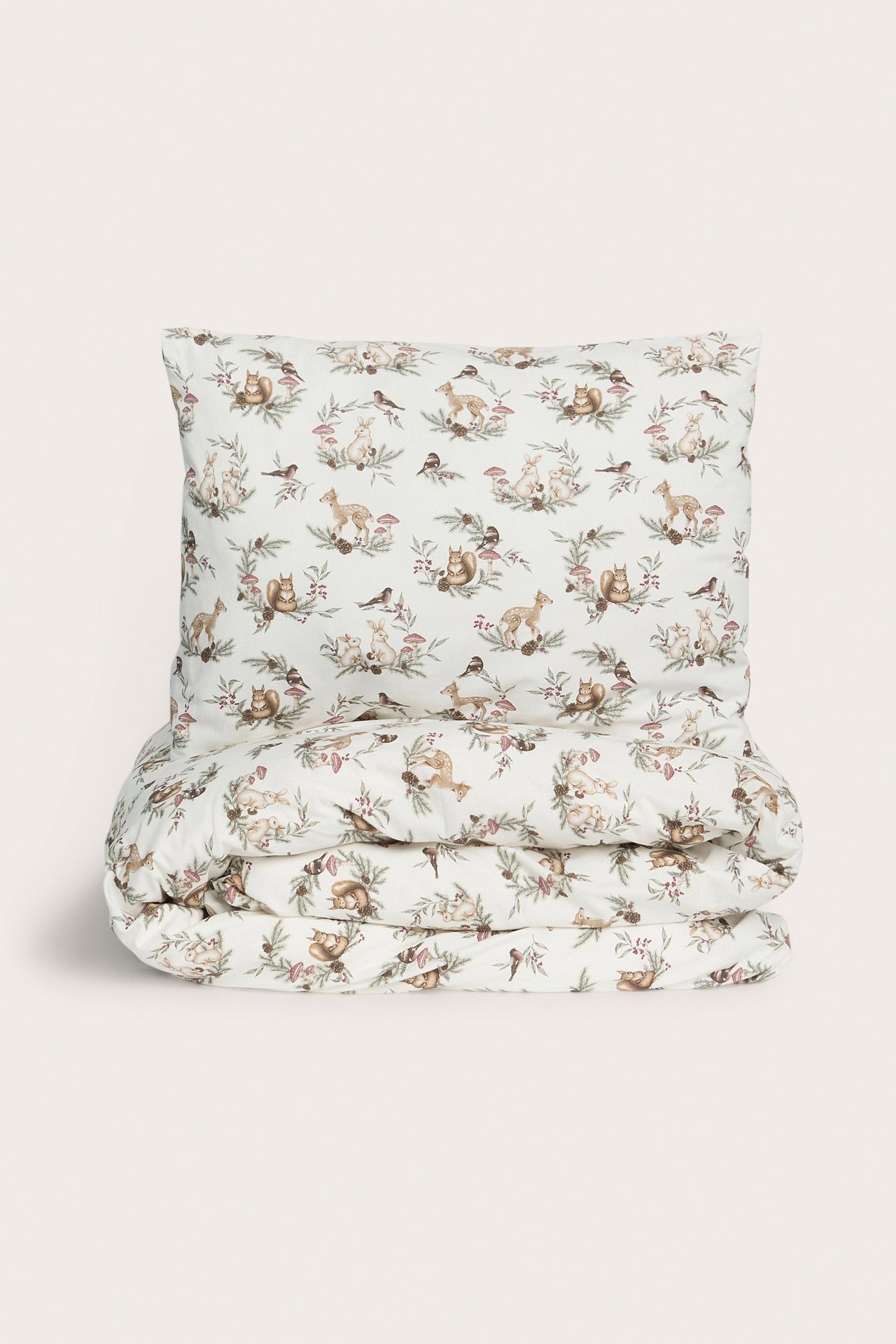 Vorderansicht eines cremeweißen Baumwoll-Bettwäsche-Sets mit weihnachtlichem Tier- und Pflanzenmuster.