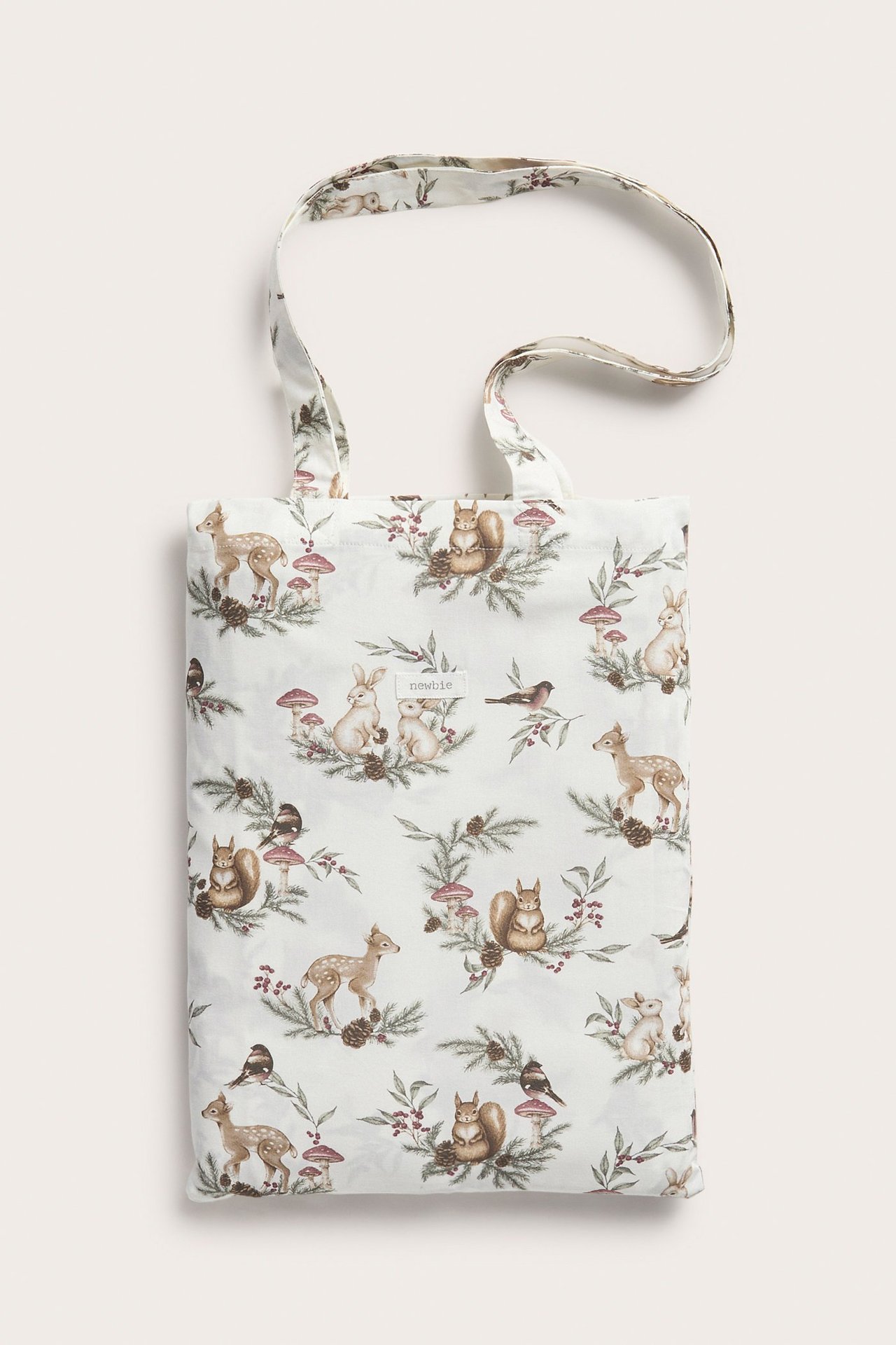 Vorderansicht einer cremefarbenen Baumwolltasche mit weihnachtlichem Waldtier- und Pflanzenmuster.