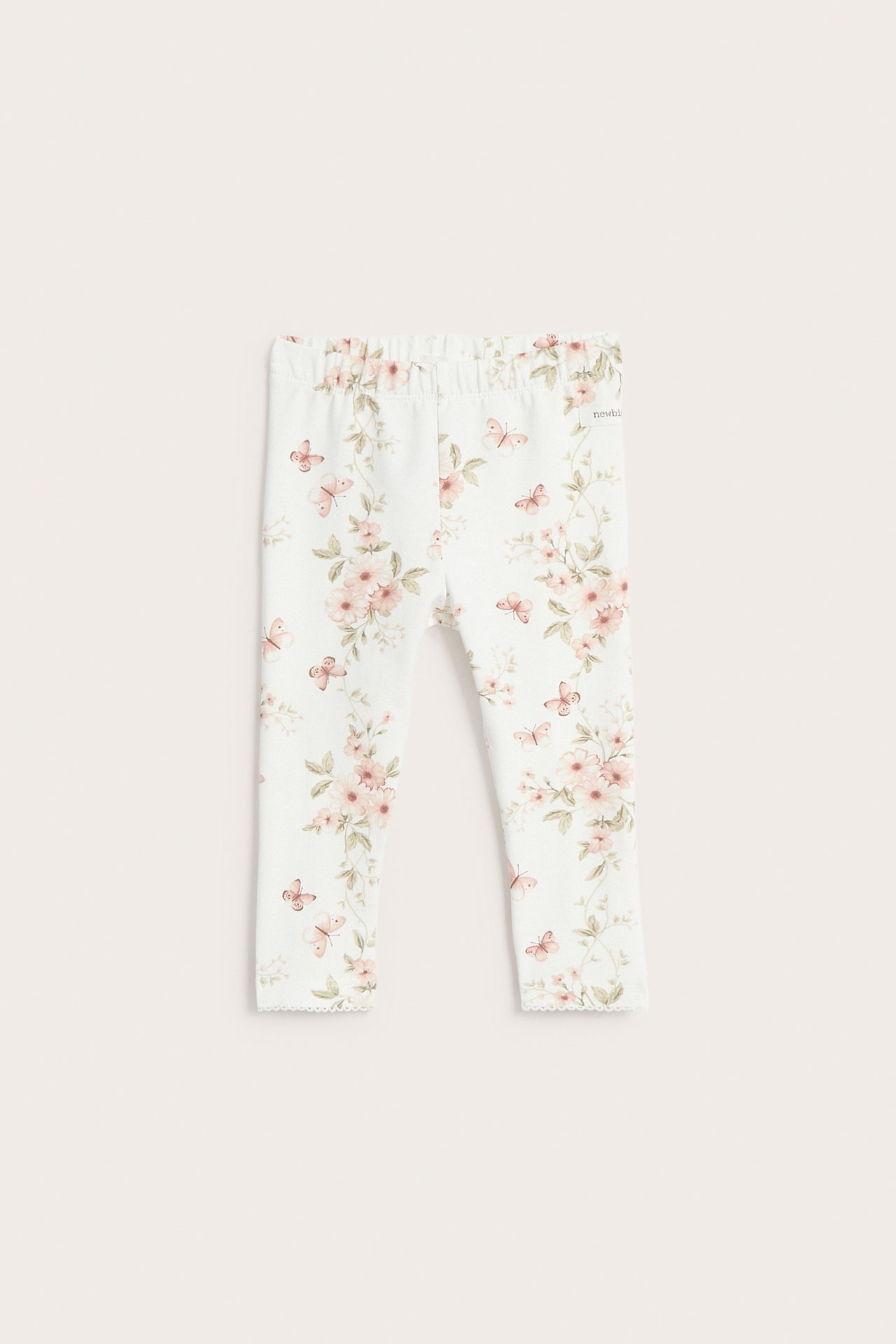 Front view: Off-white baby leggings with elastic waist, pink floral-butterfly print, and picot trim.