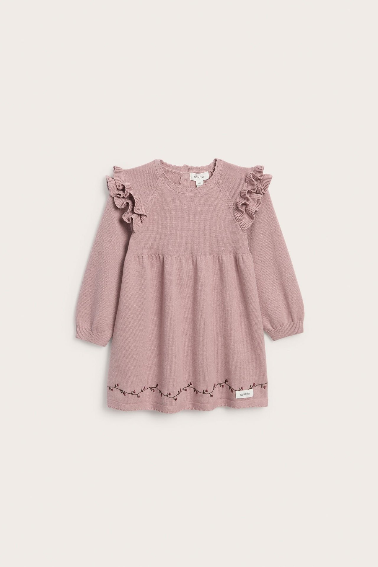 Vorderansicht eines rosa gestrickten Babykleides mit Schulterrüschen und gestickten Rankendetails.