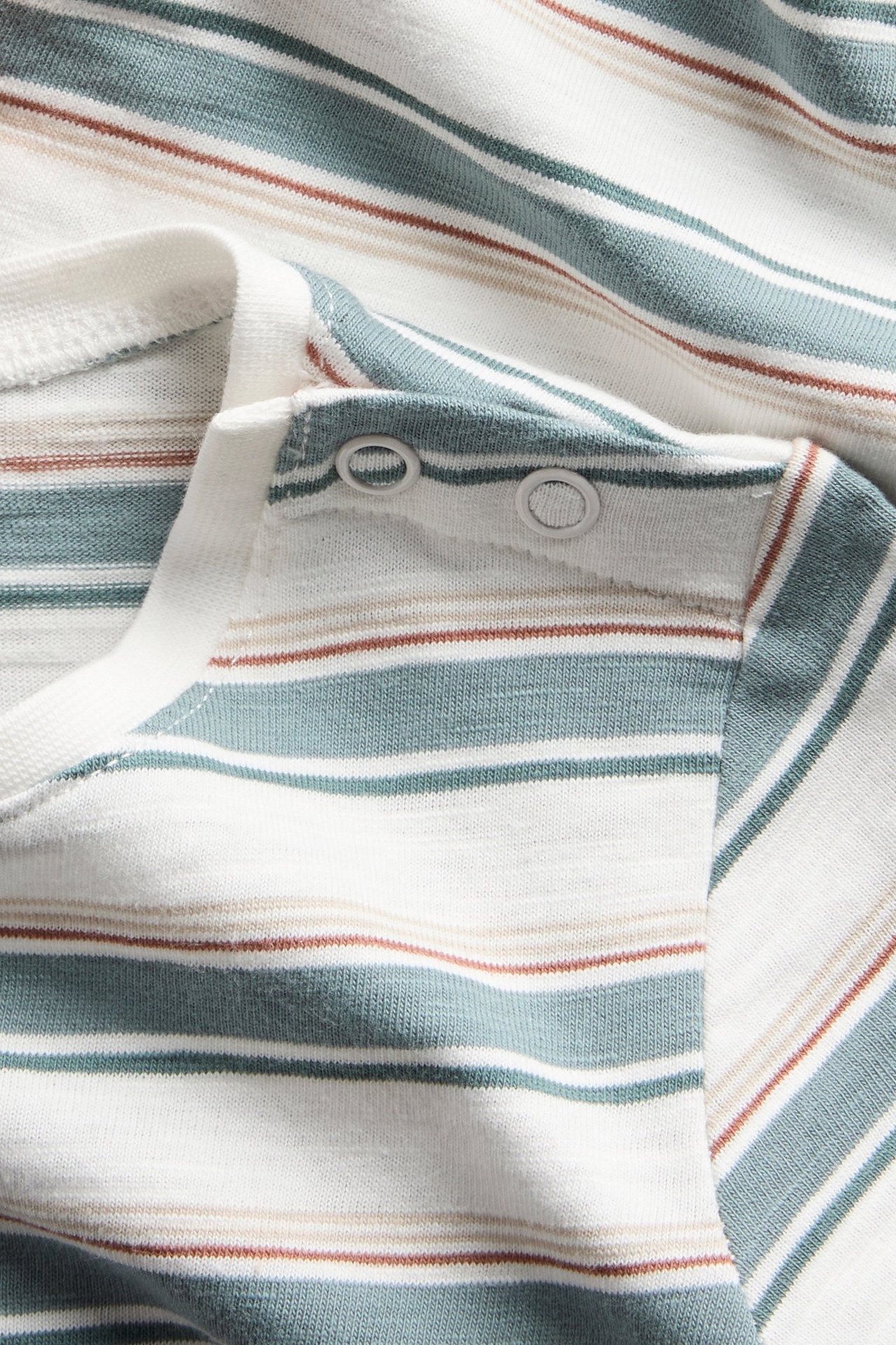 Nahaufnahme eines off-white Baby-Bodys mit kurzen Ärmeln, türkis-braunen Streifen und Druckknöpfen an der Schulter.