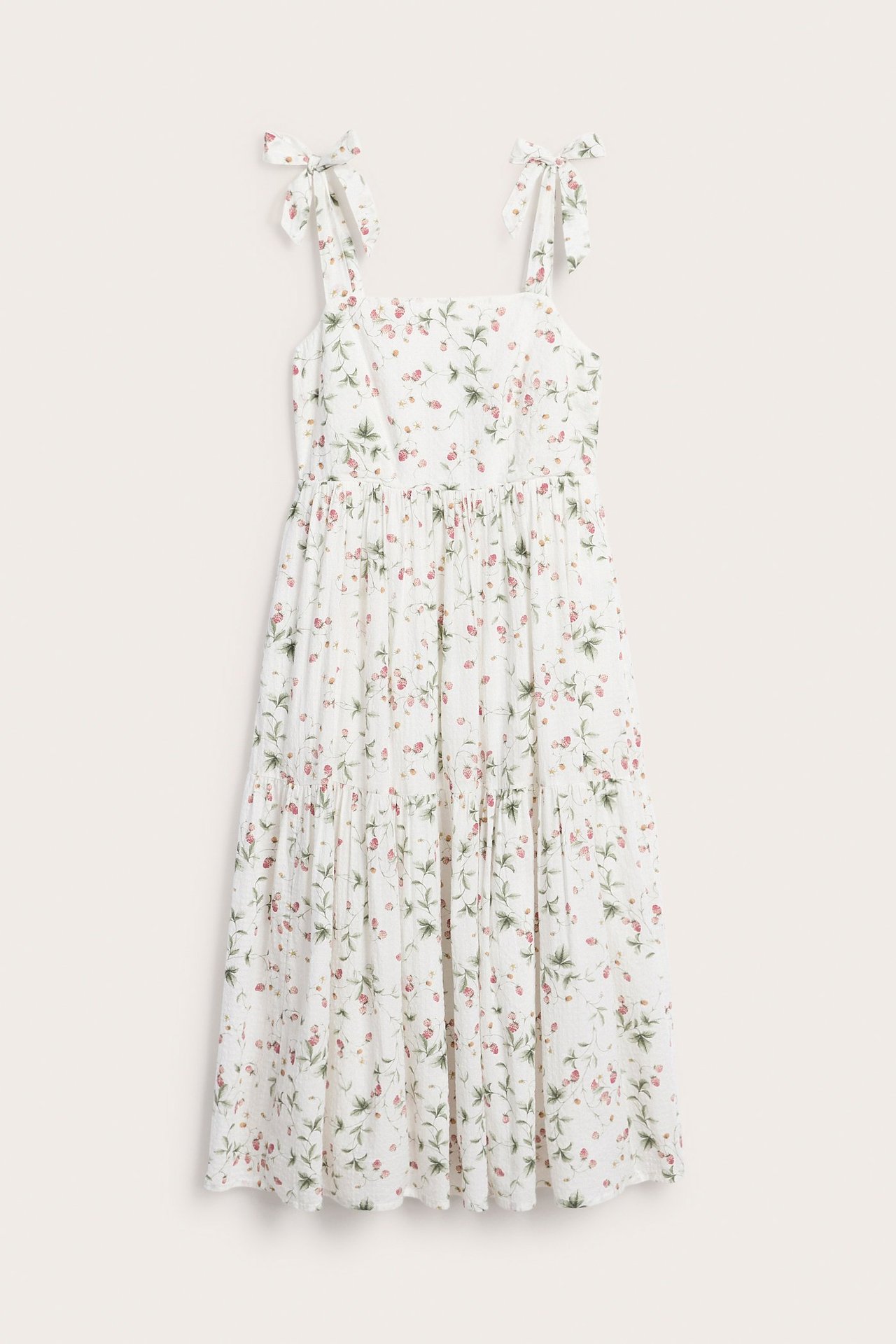 Front view of an off-white cotton midi dress with red strawberry pattern and tie shoulder straps.
