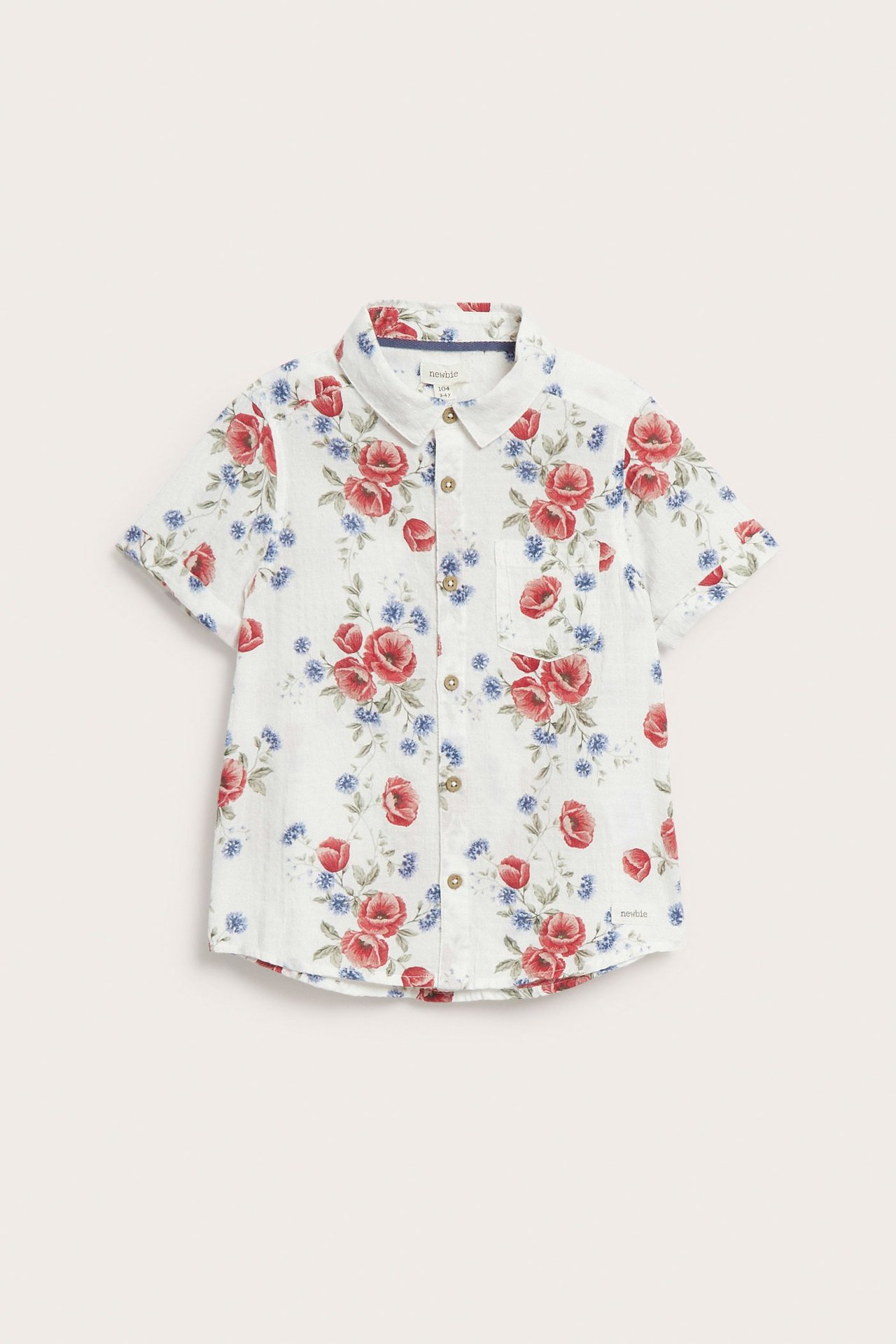 Front view of a kid's offwhite short-sleeved cotton shirt with red and blue floral print and buttons.