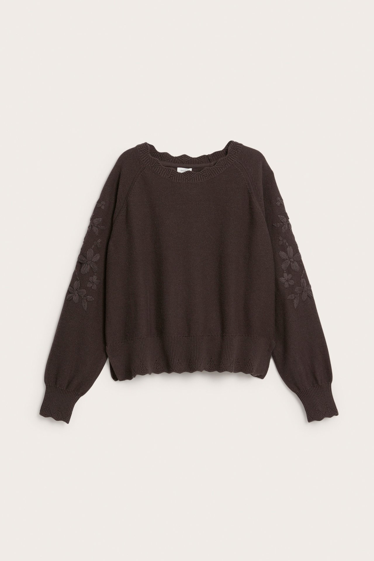 Front view of a dark brown knit sweater with scalloped edges and embroidered floral sleeves.
