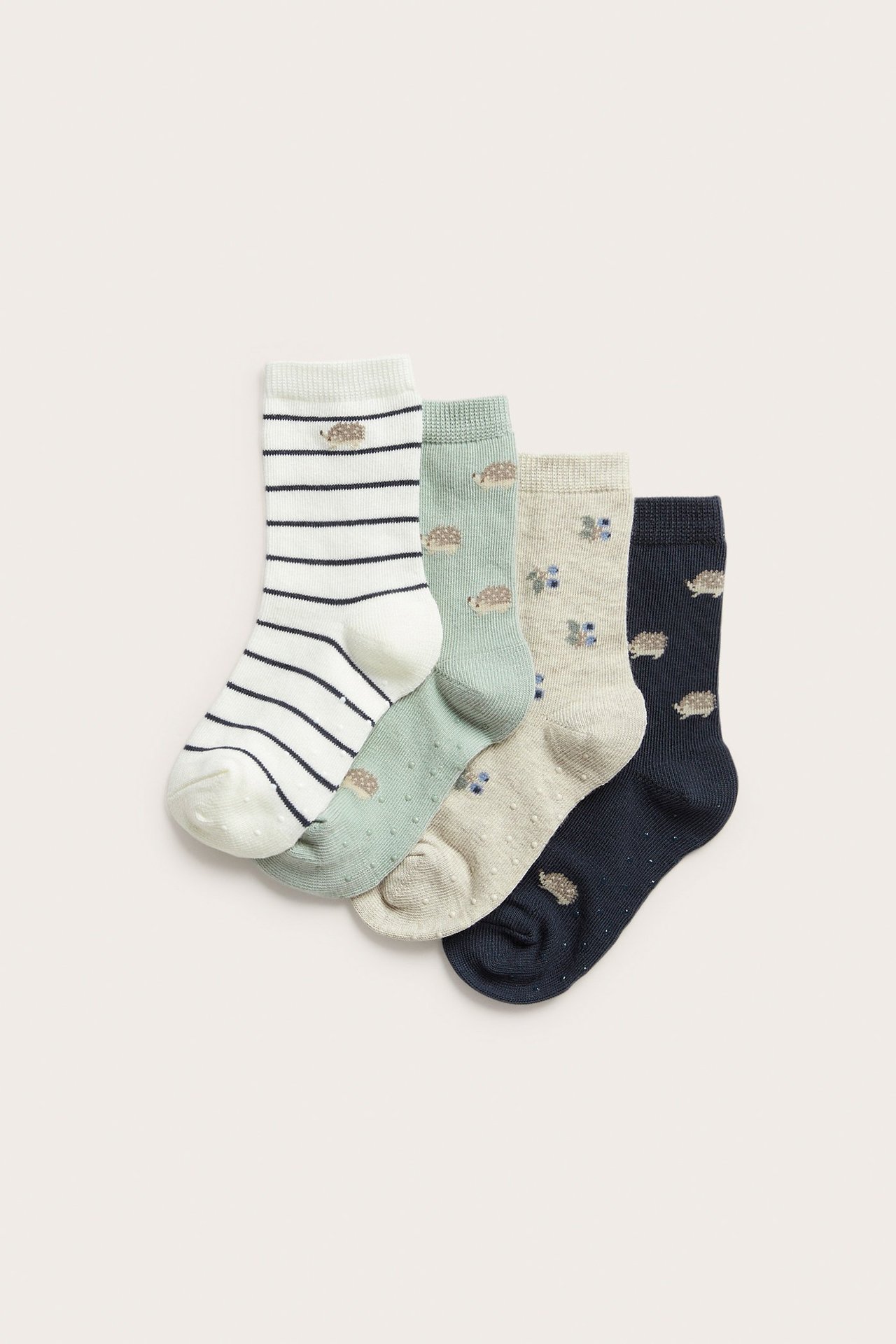 Flat lay of four patterned kids' socks: dark blue, green, striped, beige, with hedgehogs, blueberries, anti-slip.