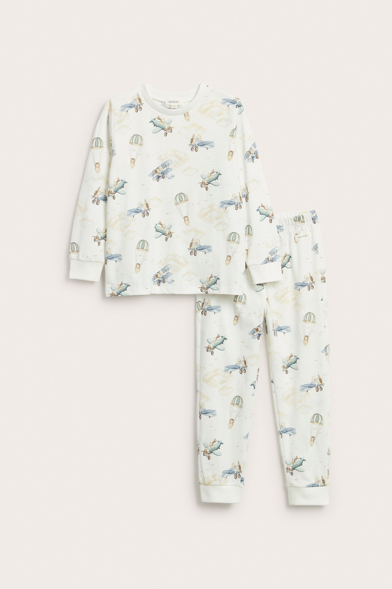 Front view of an off-white two-piece kid's pajama set featuring planes, bears, and hot air balloon print.