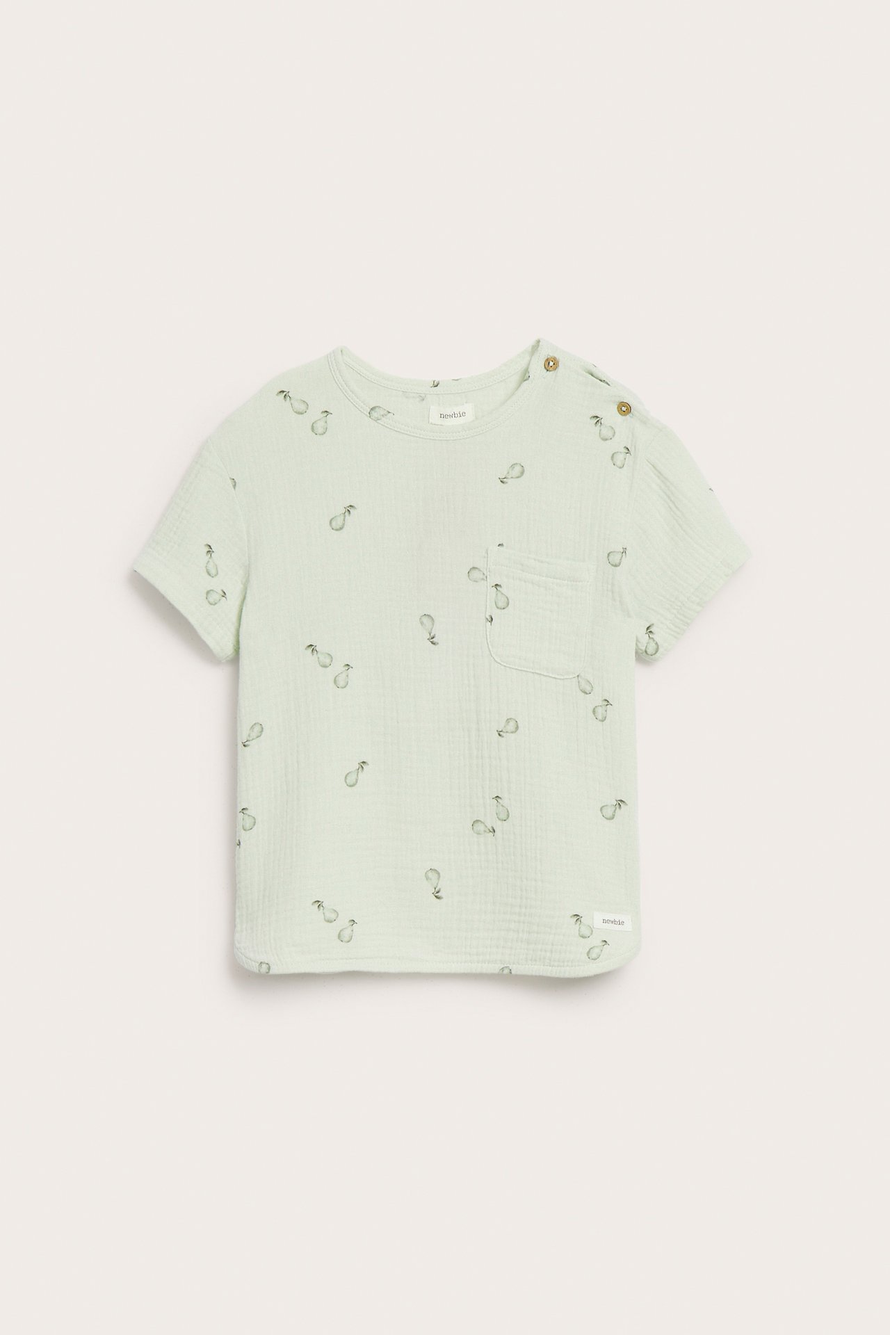 Front view: Light green cotton muslin kid's top with pear pattern, chest pocket, and shoulder buttons.