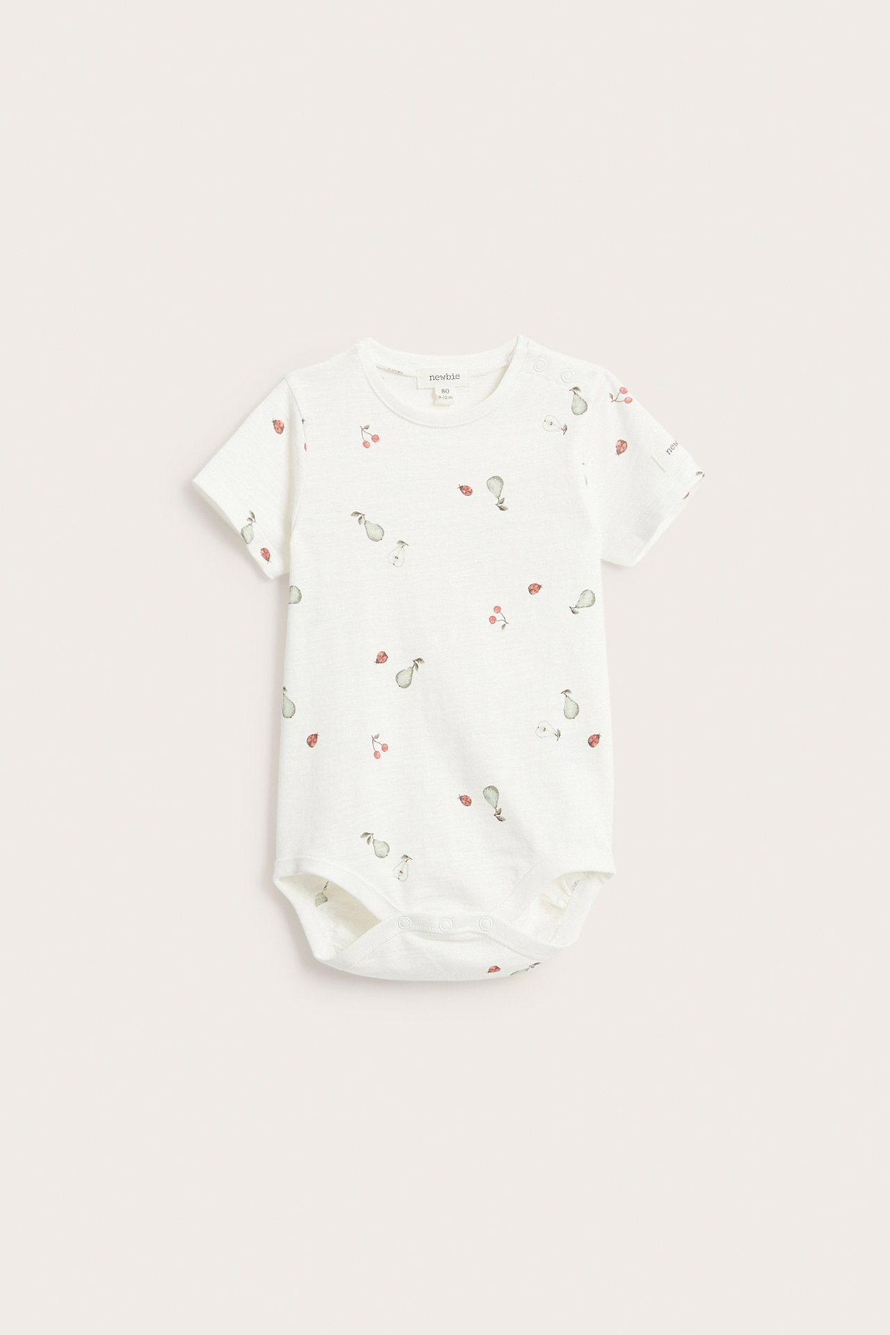Vorderansicht eines cremeweißen Baby-Kurzarmbodys aus Baumwolle mit Birnen-, Kirsch- und Marienkäfermuster.