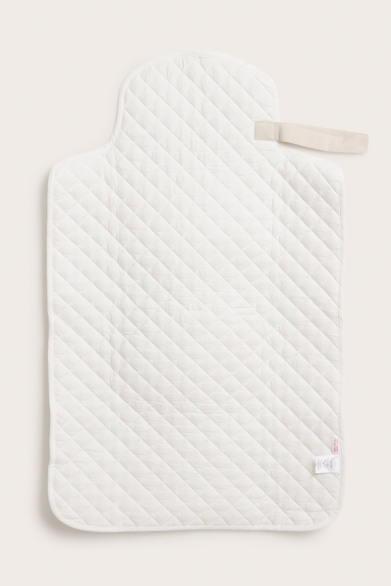 Top view of an off-white, quilted, padded, foldable changing pad with a light beige carrying handle.