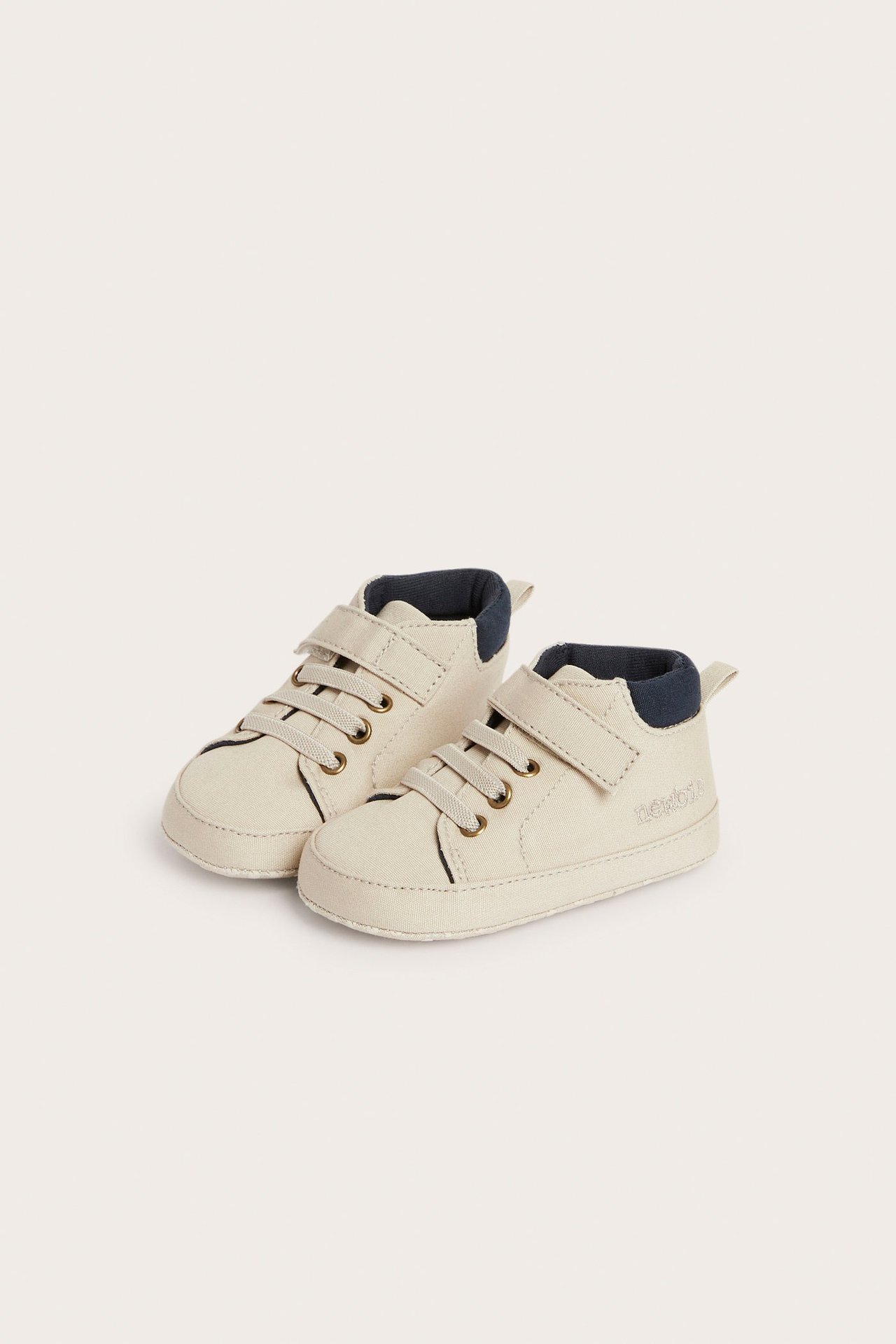 Vorderansicht eines Paares beiger Baby-High-Top-Schuhe mit elastischen Schnürsenkeln und Klettverschluss.