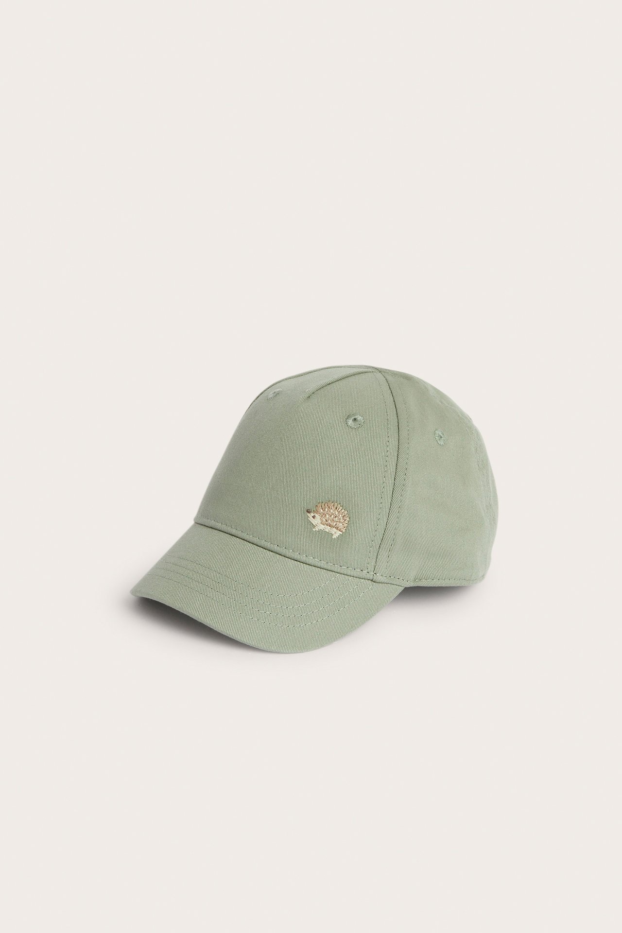 Front view of a light green kids' cap with a small hedgehog embroidery on the front.