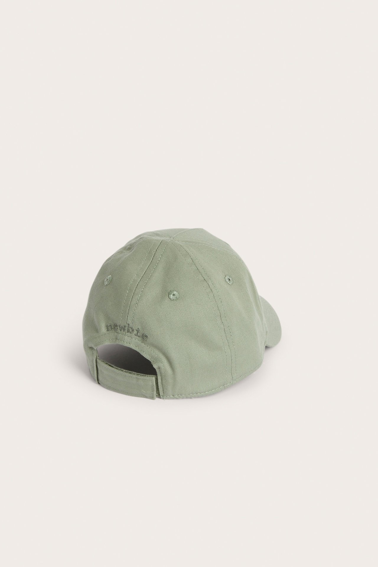 Back-side view of a kid's sage green cotton cap with an adjustable strap and 'newbie' embroidery.