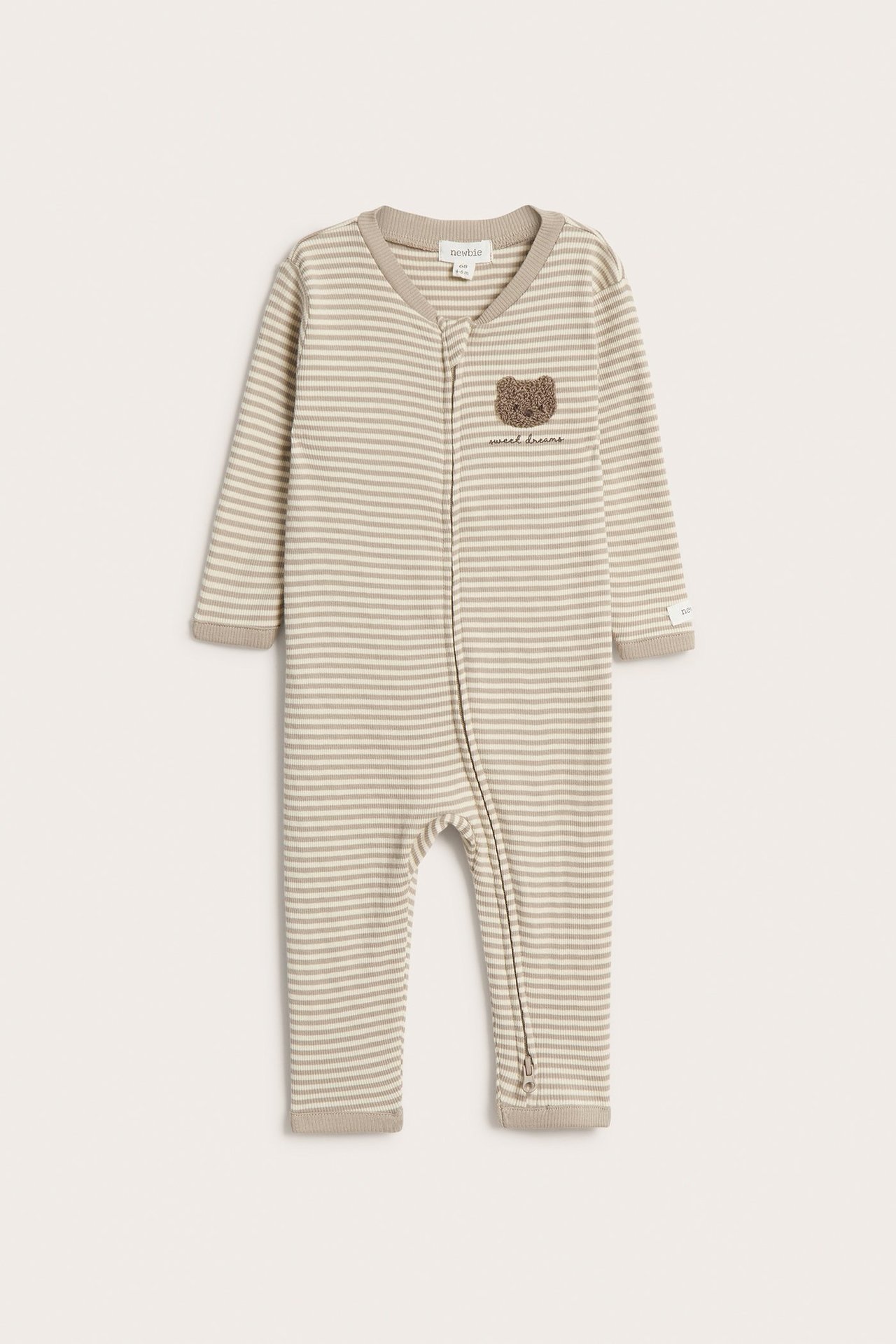Vorderansicht: Baby-Schlafanzug in beige gestreiftem Rippstrick mit Zwei-Wege-Reißverschluss und Teddy-Applikation.