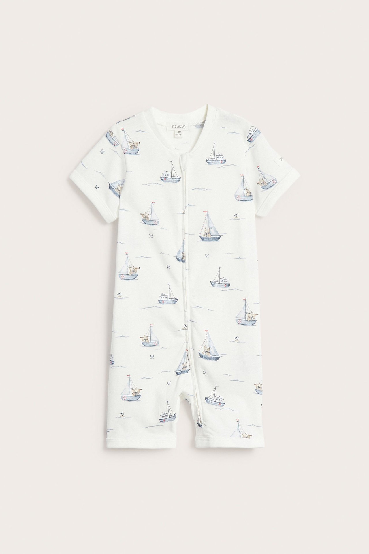 Front view: Off-white baby romper in cotton jersey with sailboat pattern and front zipper.