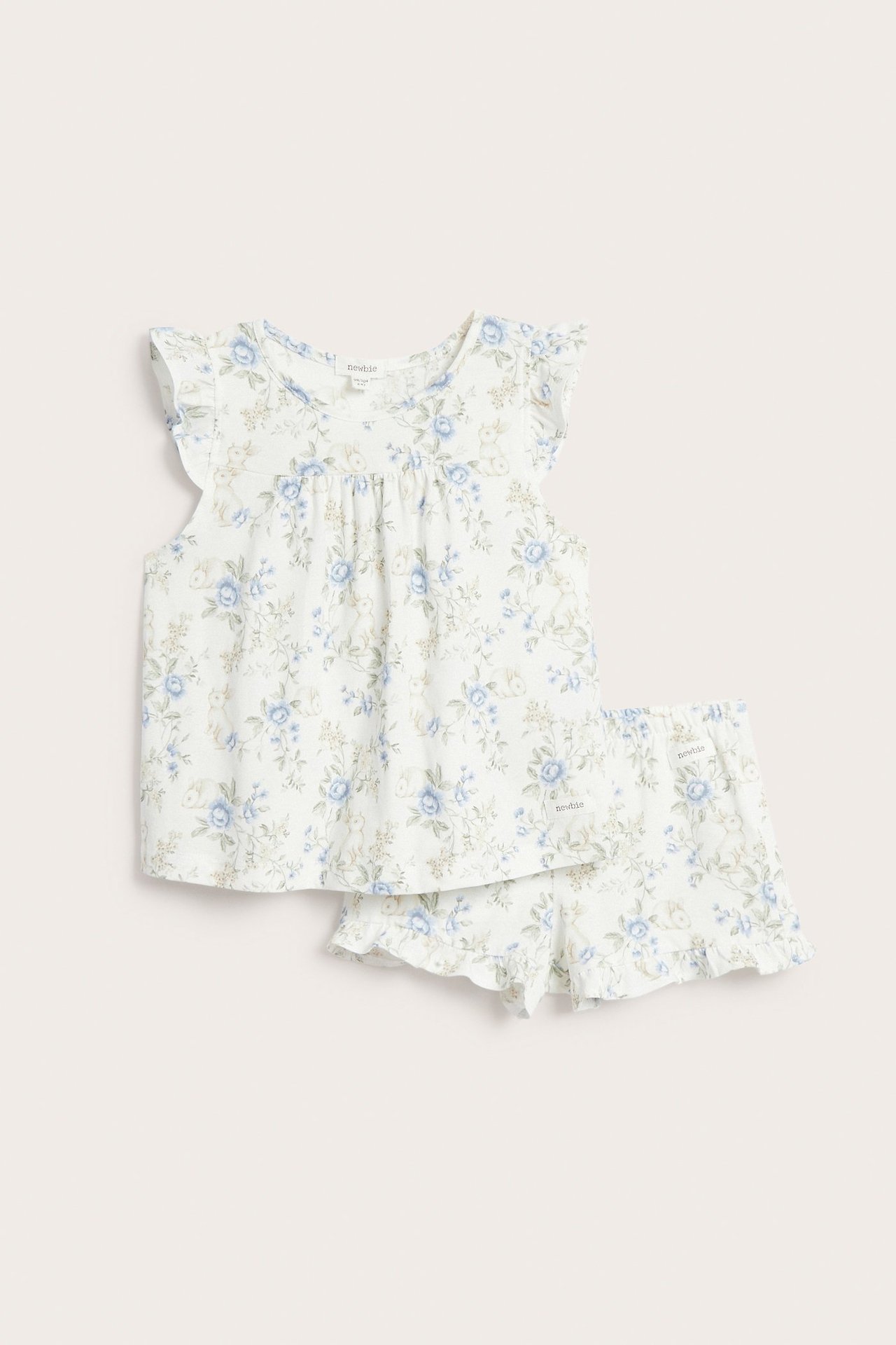 Vorderansicht: Off-white Baby-Pyjama mit blauem Blumen- und Hasenmuster, Rüschenärmeln und Shorts.