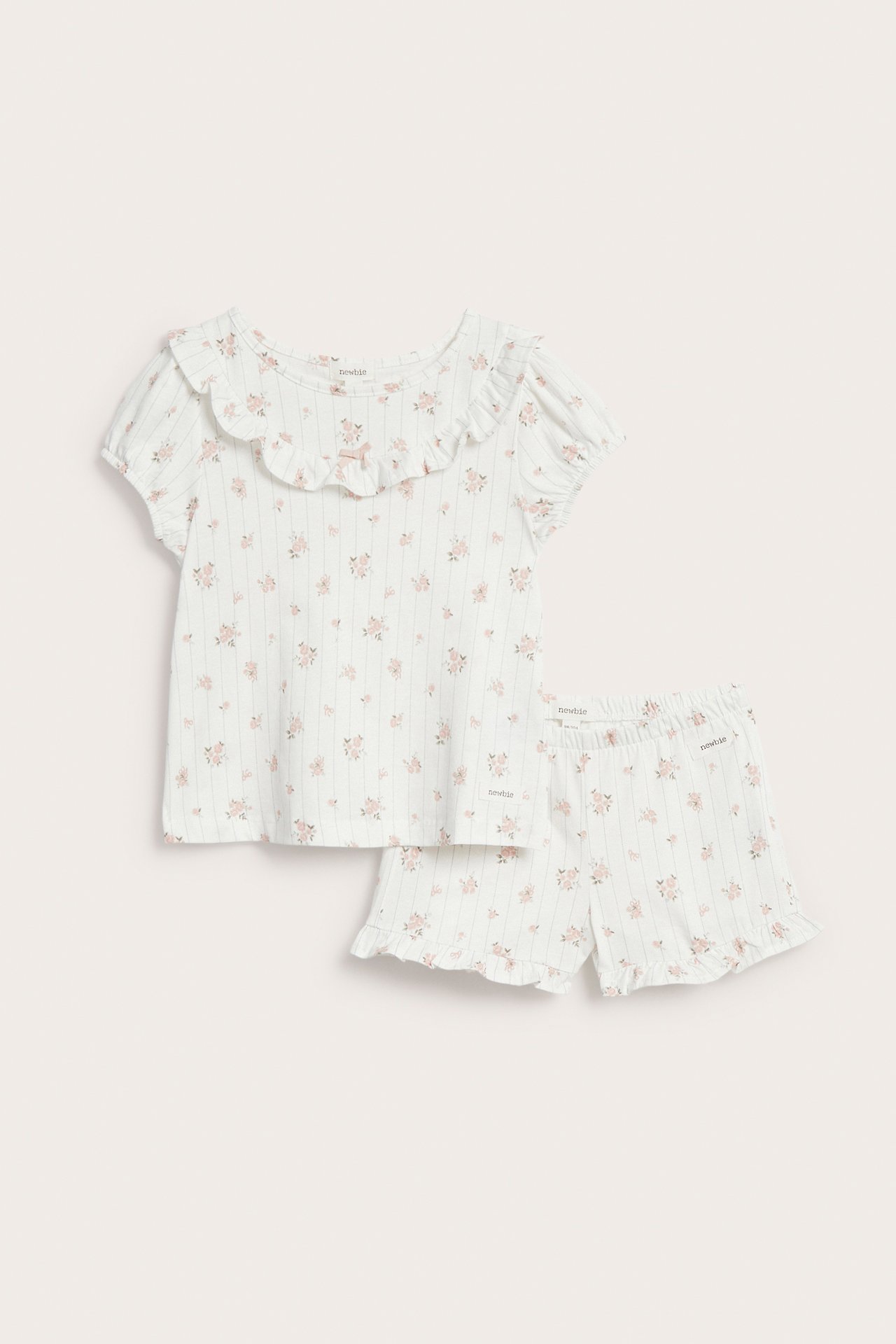 Front view: Kid's off-white cotton floral pyjama set. Ruffled collar top with puff sleeves and matching ruffled shorts.