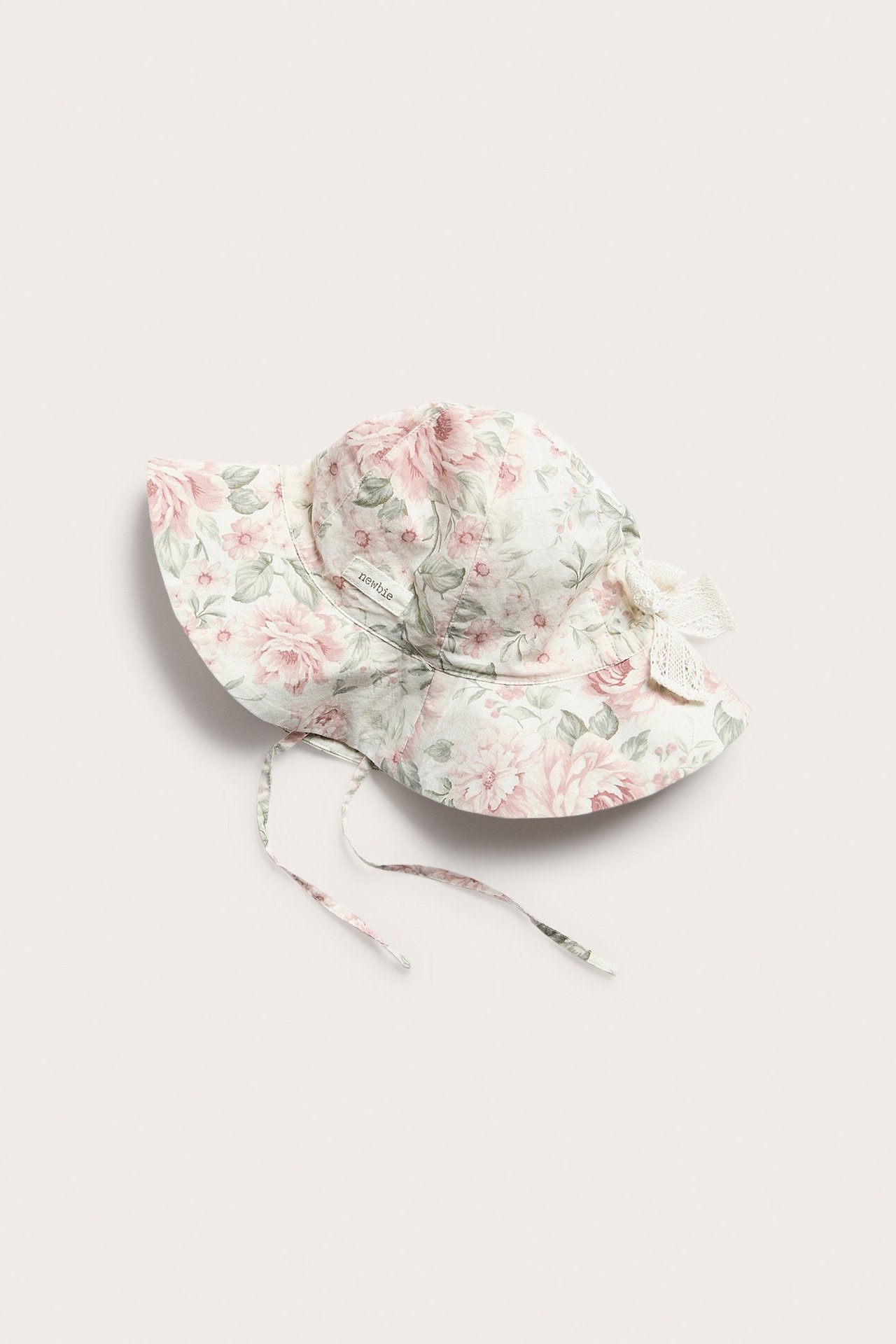Top-down view of an offwhite floral sun hat with a wide brim, tie bands, and a lace bow.