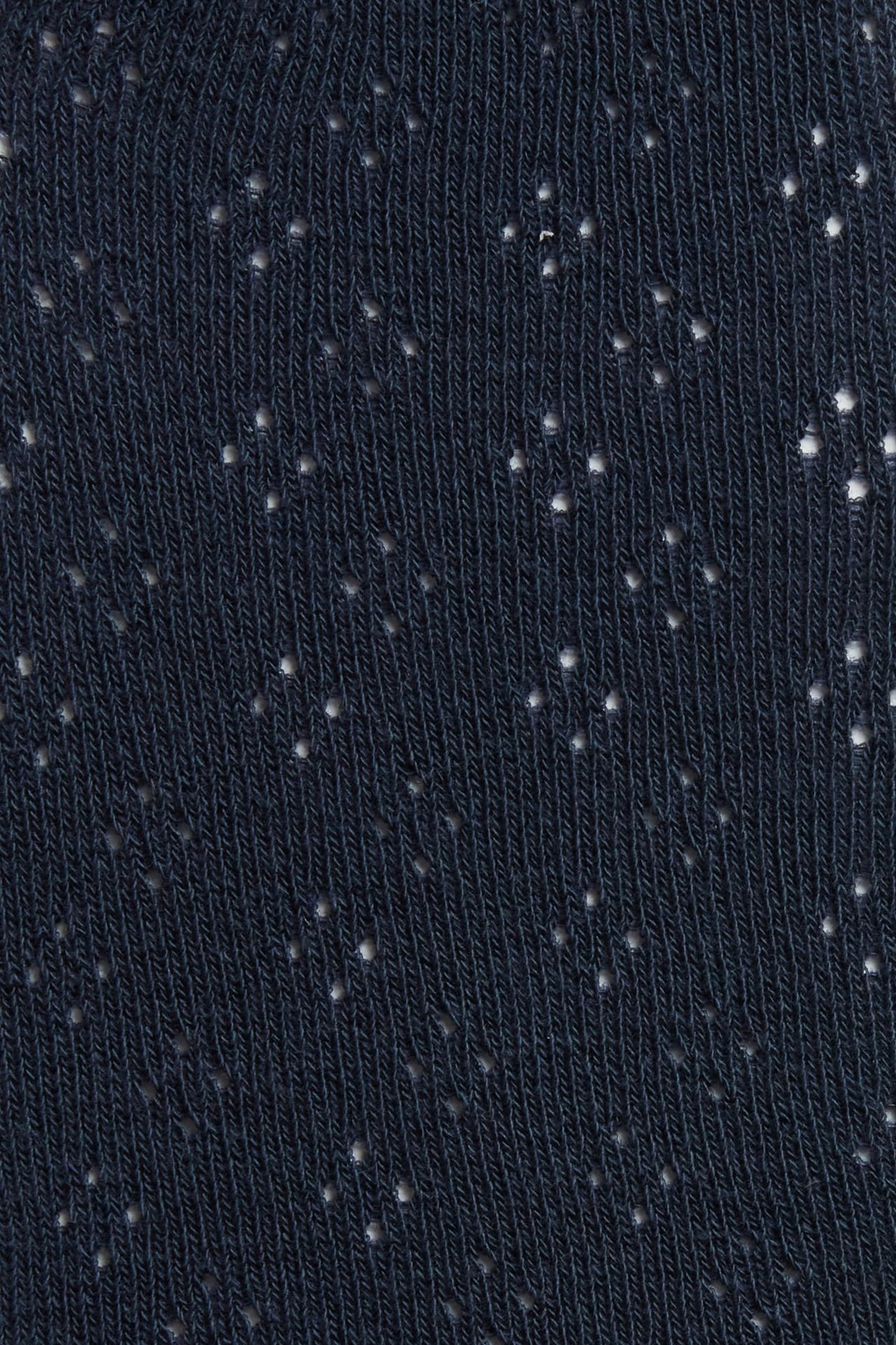 Close-up of dark blue tights with a knitted hole pattern texture.