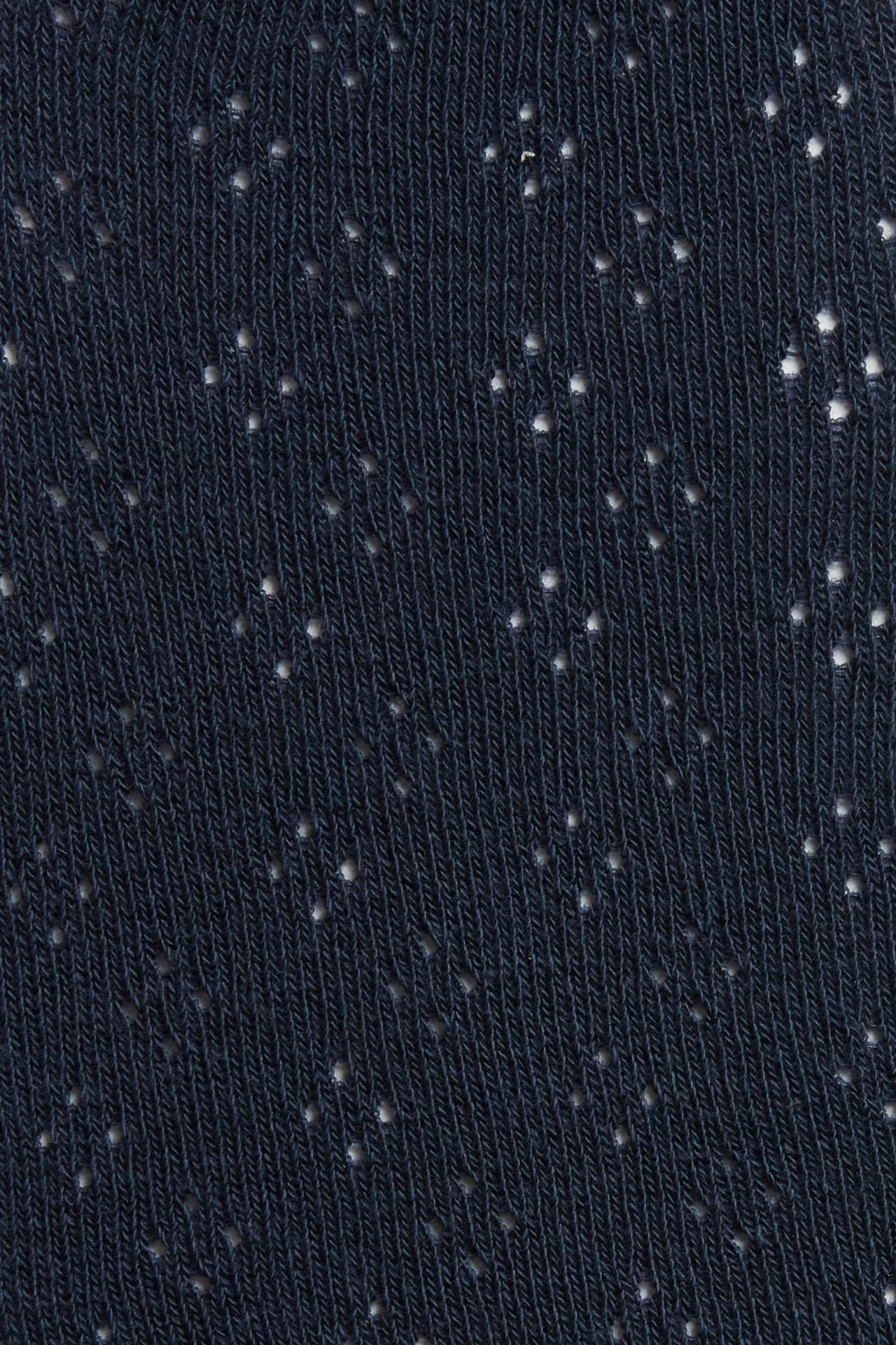 Close-up of dark blue tights with a subtle knitted hole pattern.
