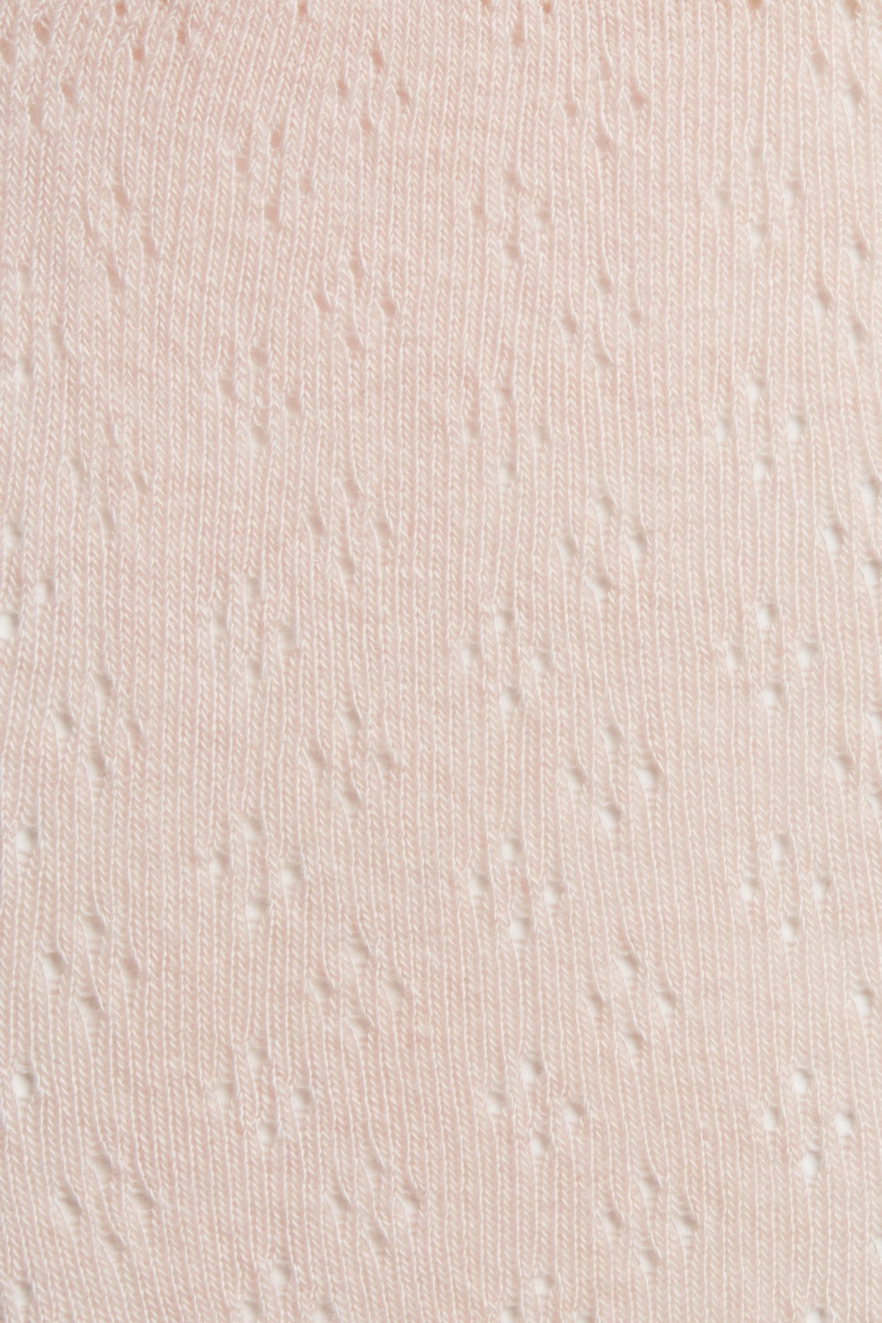 Close-up of light pink tights fabric with a delicate hole pattern.