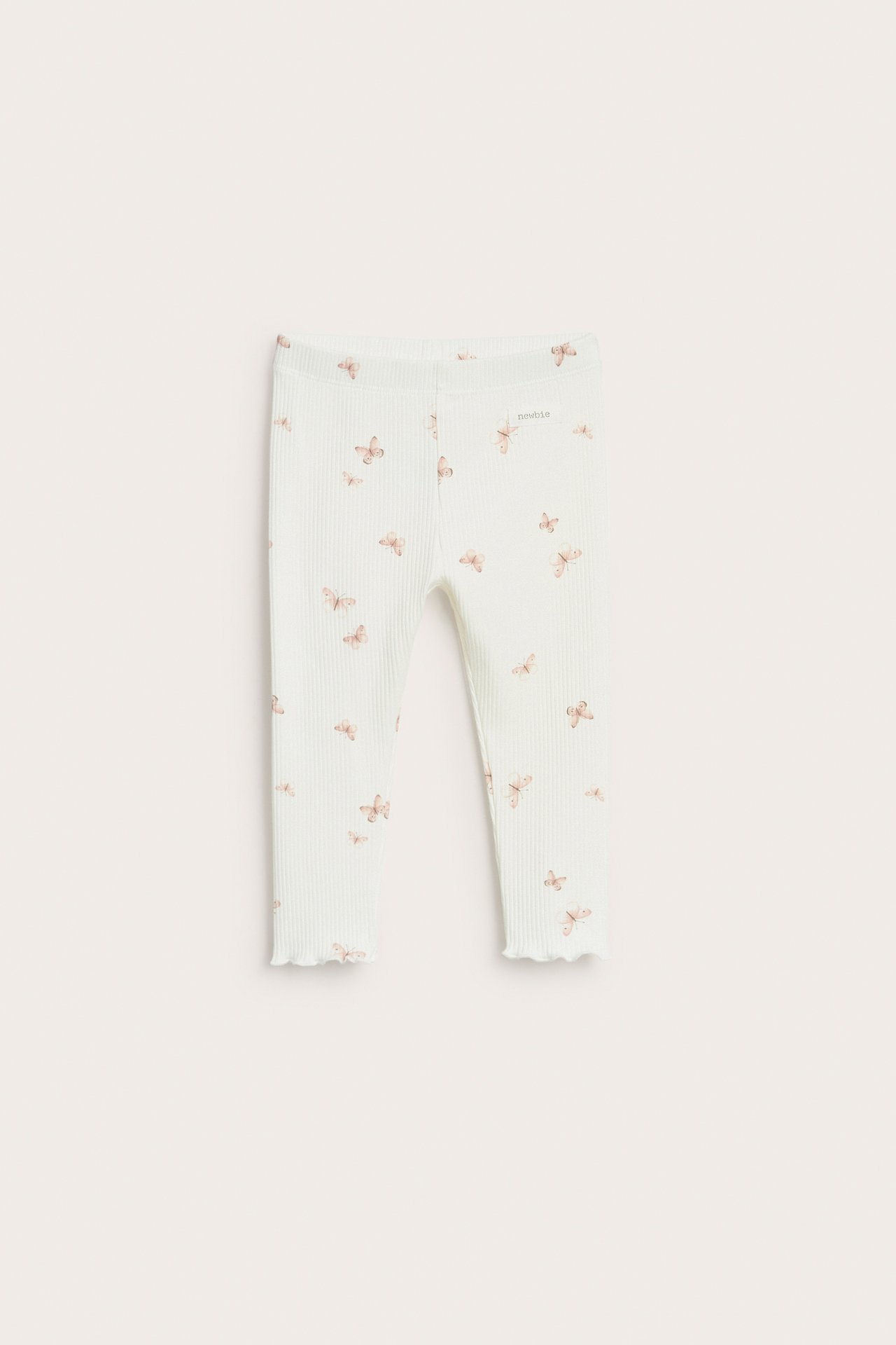 Front view of baby's off-white ribbed leggings with a light brown butterfly pattern and wavy hems.