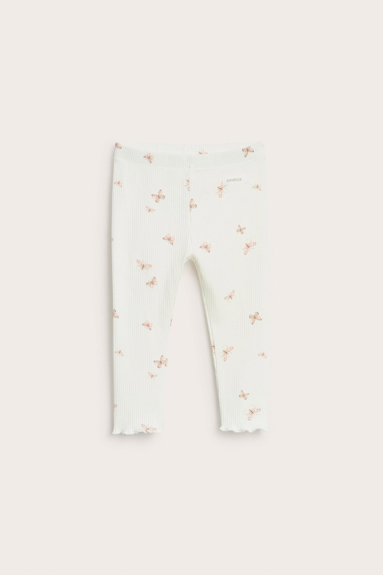 Vorderansicht: Off-white gerippte Baby-Leggings mit zartem Schmetterlingsmuster und welligem Saum.