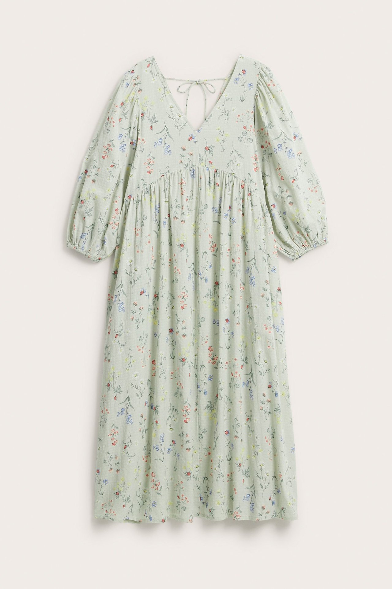 Front view of a light green floral cotton dress with V-neck, 3/4 puff sleeves, and a back tie.