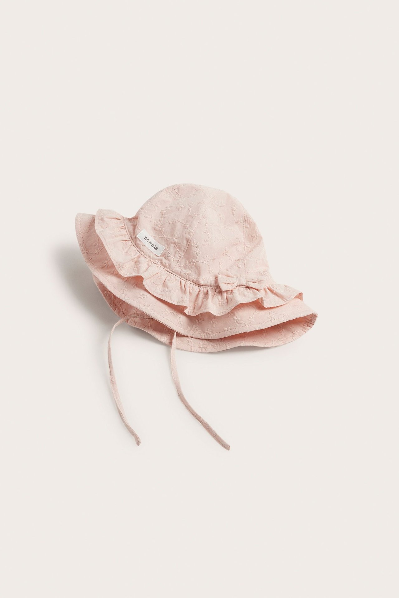 Light pink embroidered baby sun hat with ruffles and tie straps.
