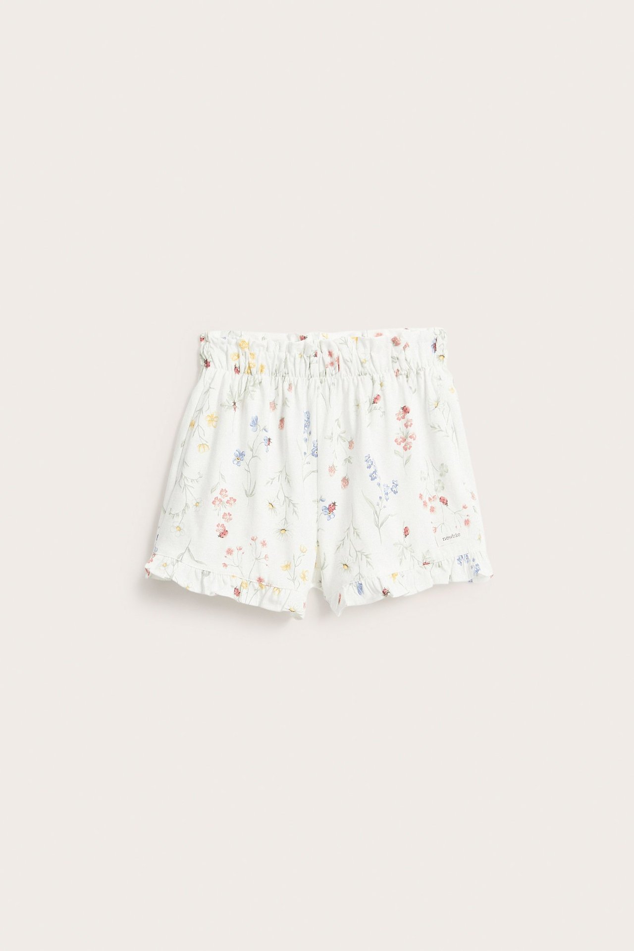 Front view: Off-white jersey shorts with floral, ladybug print, elasticated waist, ruffled legs.