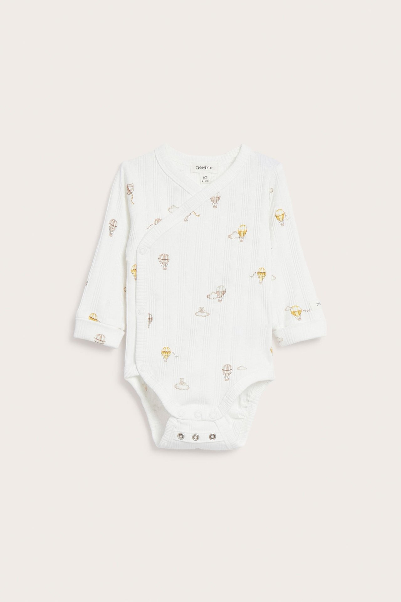 Vorderansicht: Off-weißer, gerippter Baby-Wickelbody mit Heißluftballon-Print, langen Ärmeln und Druckknöpfen im Schritt.