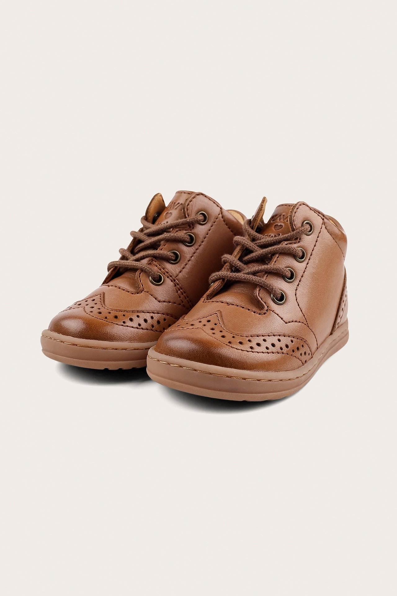 Angled front view of brown leather baby walking shoes with brogue details and brown laces.