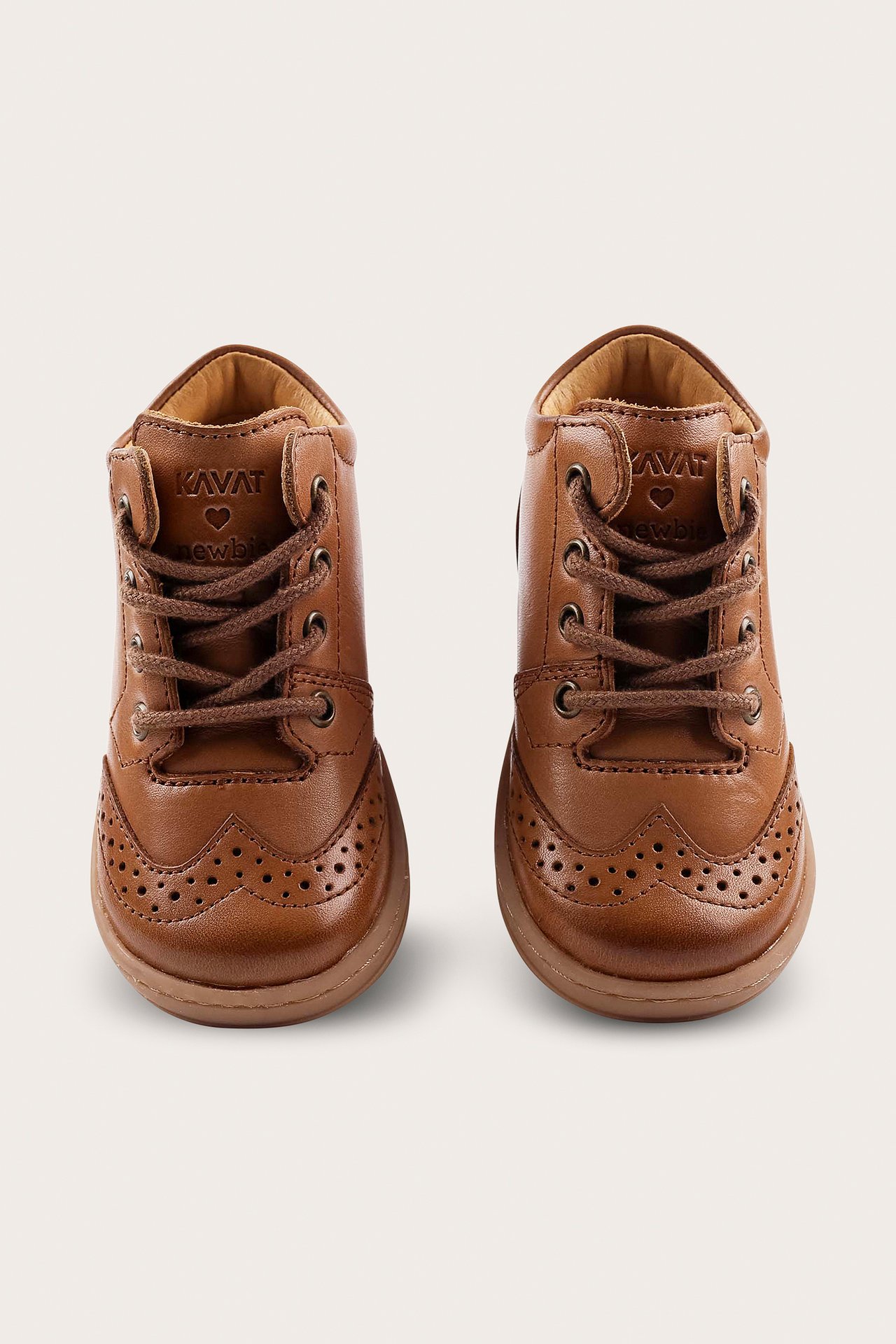 Front view of two brown leather first-walker shoes with brogue detailing and laces.