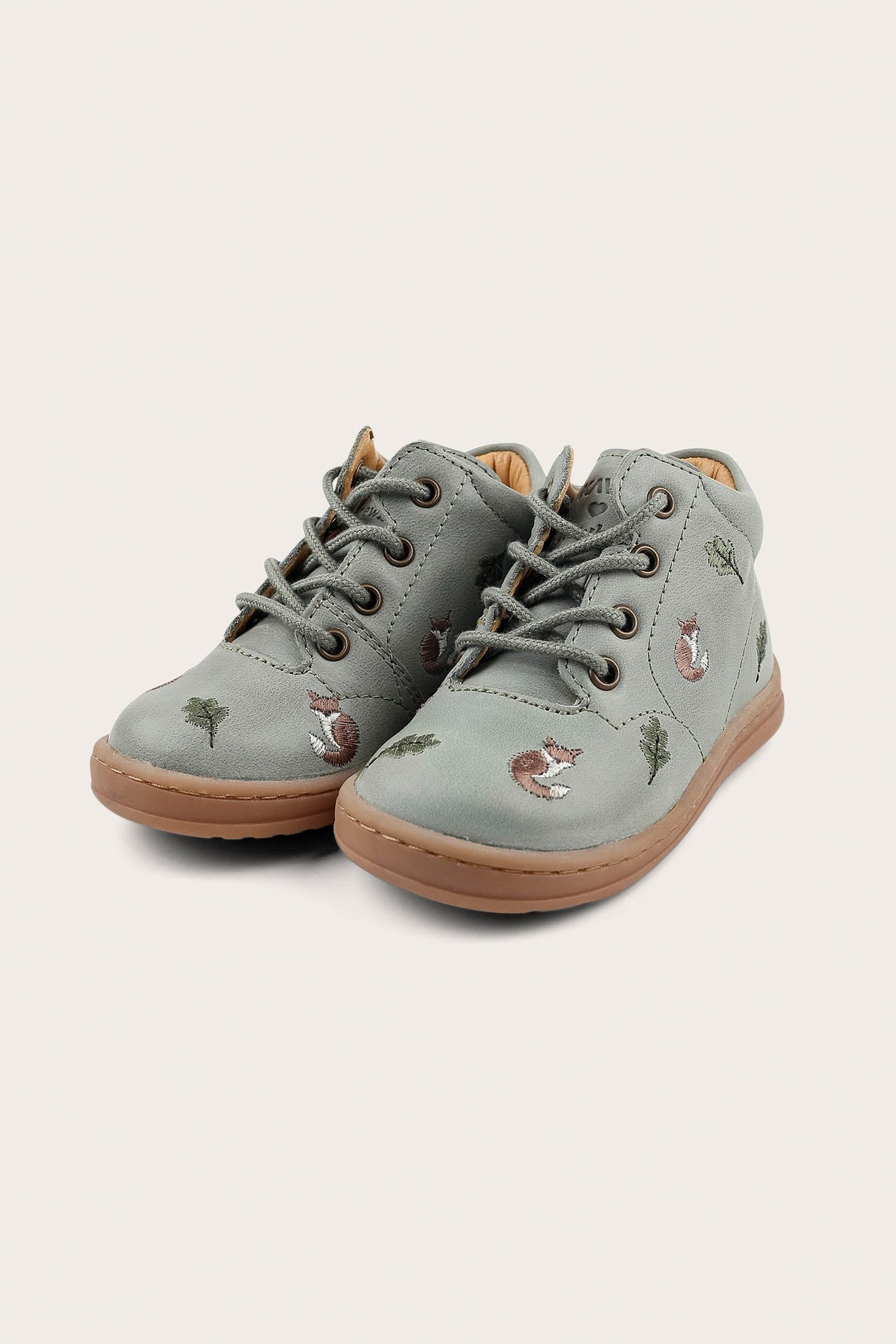 Front view of green patterned kid's shoes with fox and leaf embroidery, brown soles, and laces.