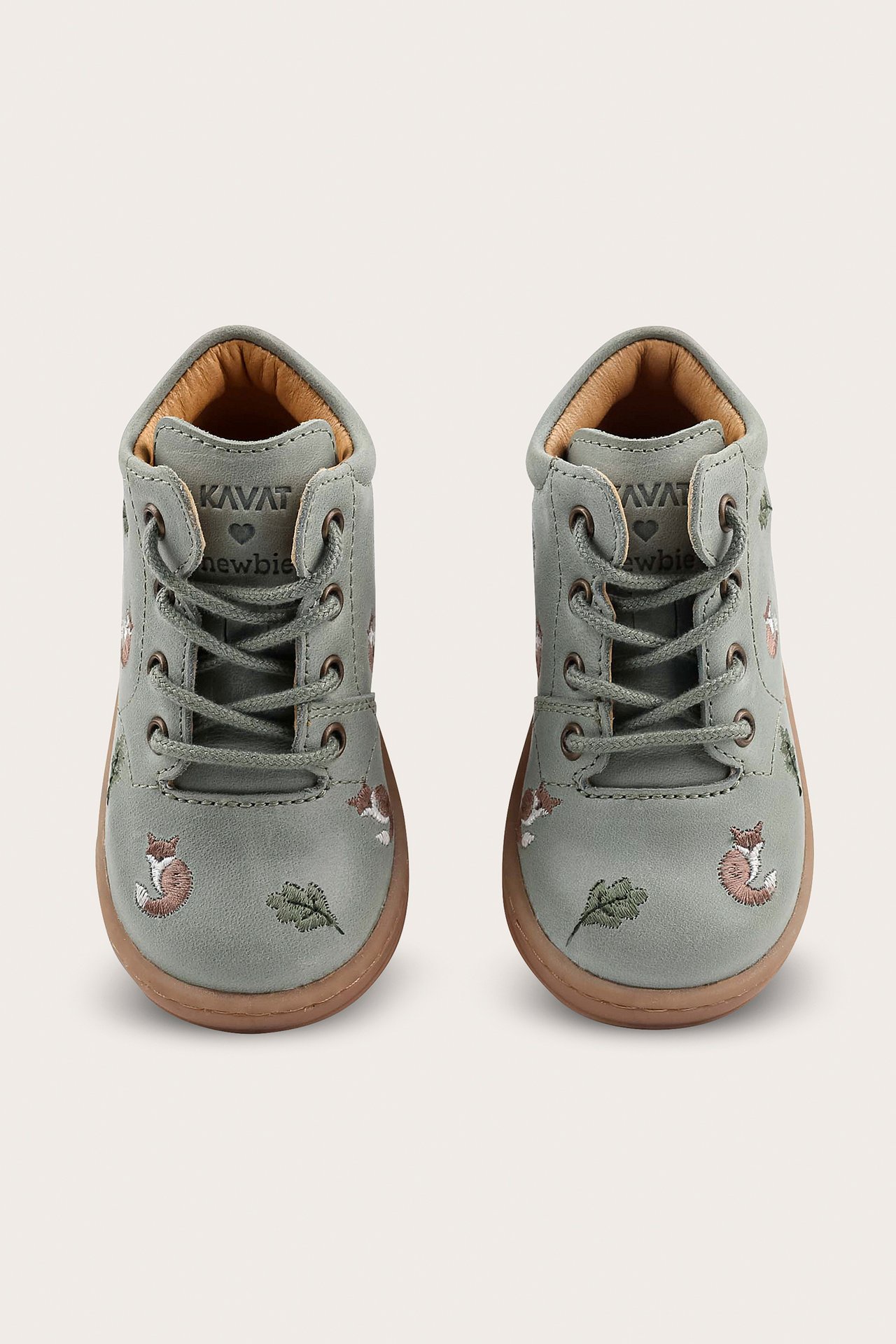 Front view of green baby shoes with embroidered foxes and leaves, fastened with laces.