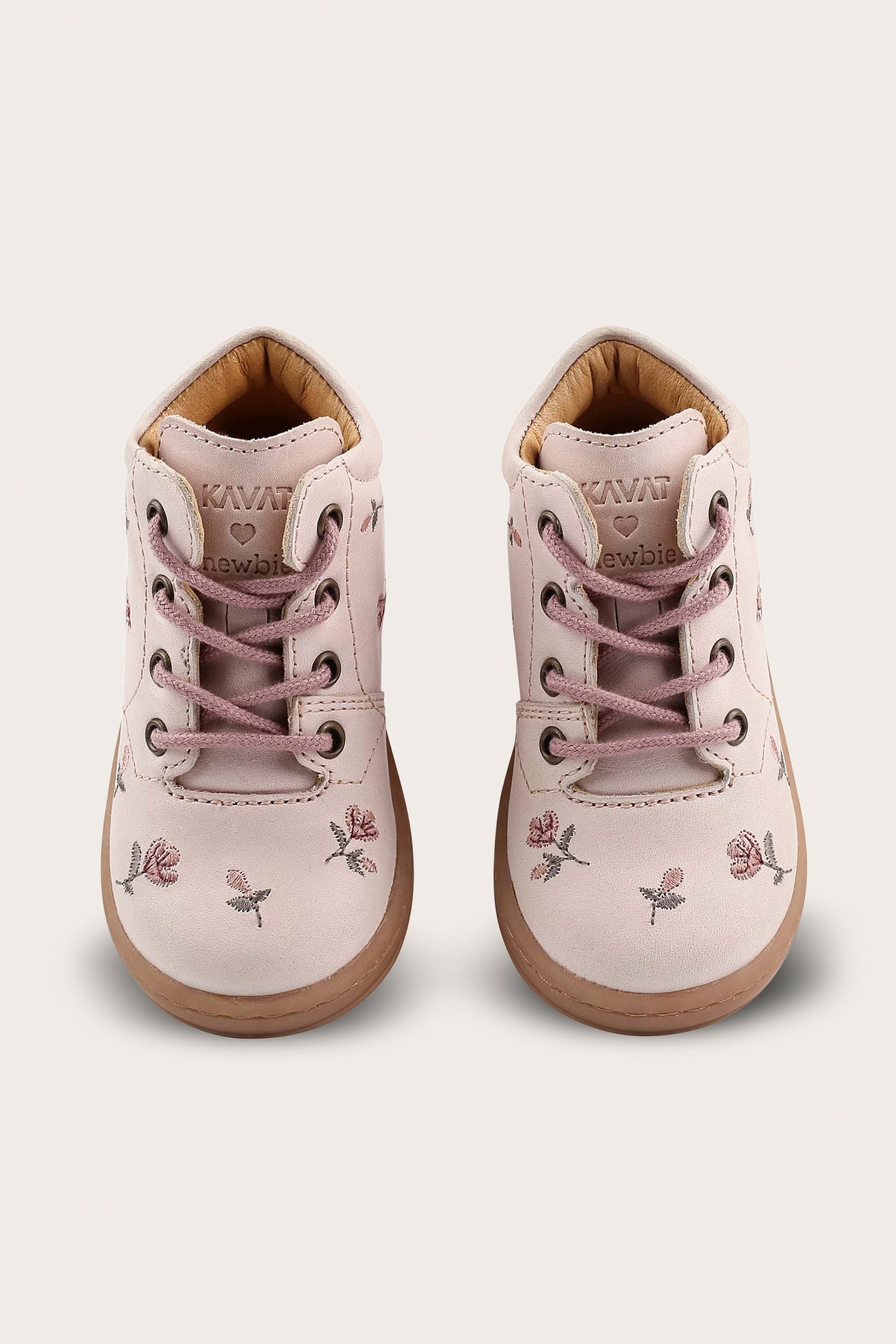 Front view of two light pink baby walking shoes with floral embroidery and pink laces.
