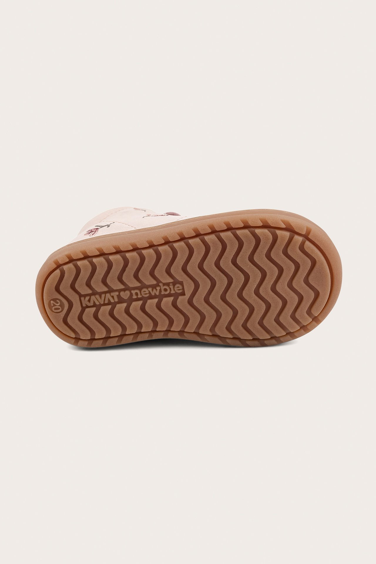 Bottom view of a light pink floral patterned baby walker shoe with a brown wavy rubber sole.