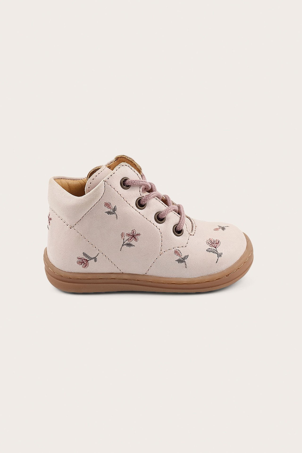 Side view of a light pink baby walker shoe with floral pattern, brown sole, and pink laces.