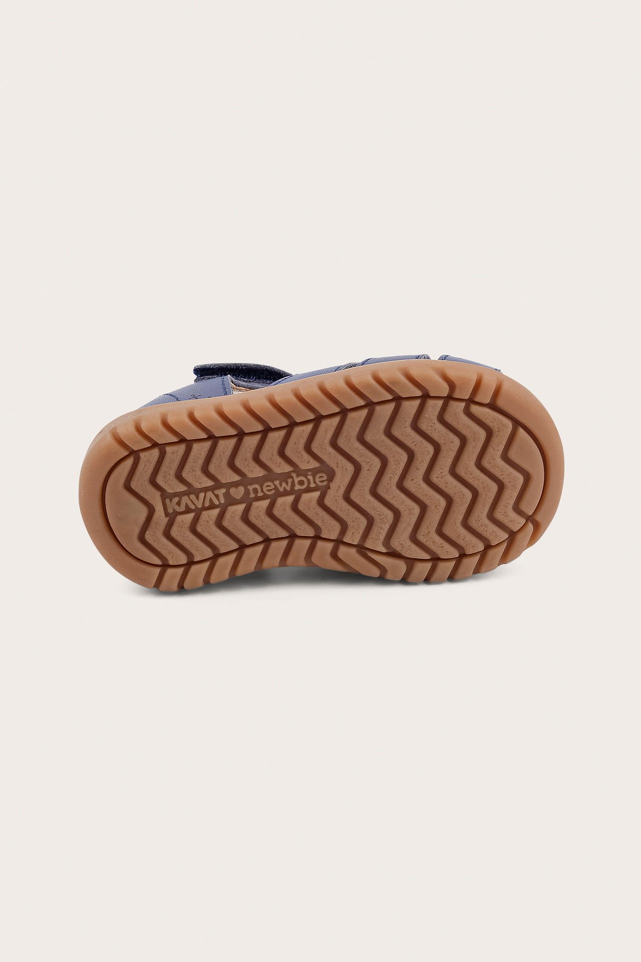 Bottom view of a blue kid's sandal with a brown rubber sole, zigzag pattern, and velcro strap.