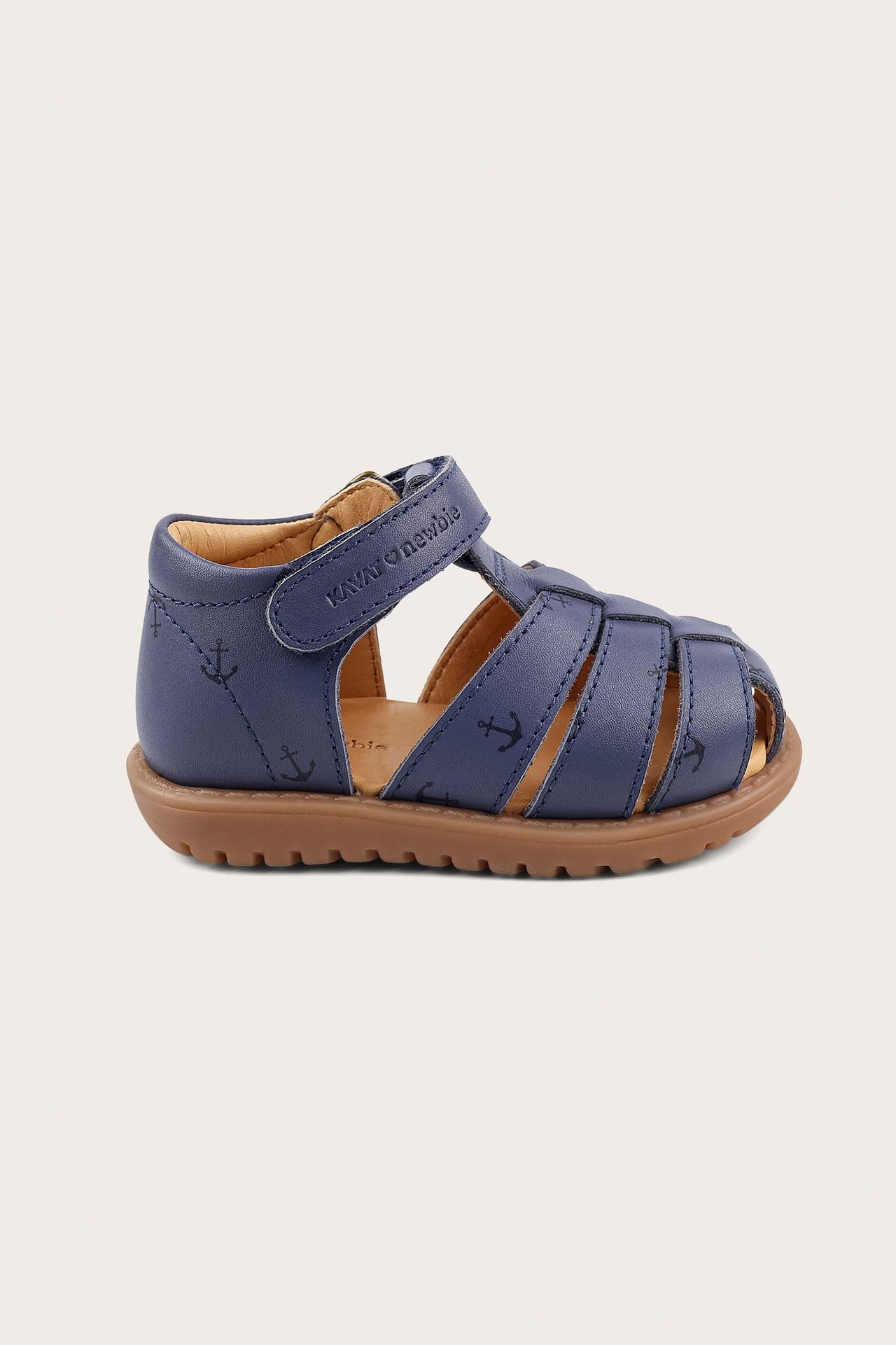 Side view of a blue kids' sandal with anchor pattern, velcro strap, and brown sole.